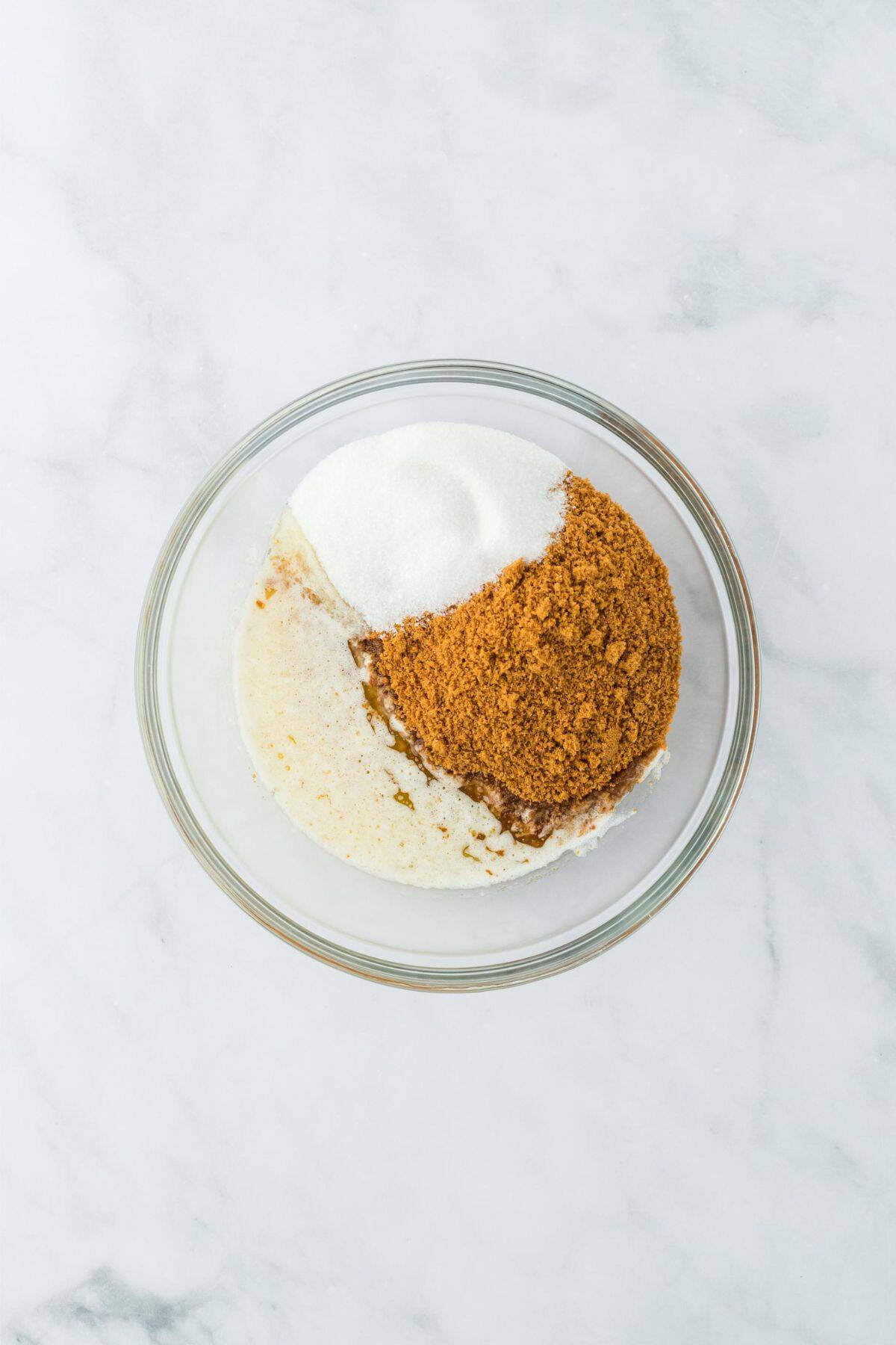 A mixture of gingersnaps, sugar, and melted butter in a glass bowl