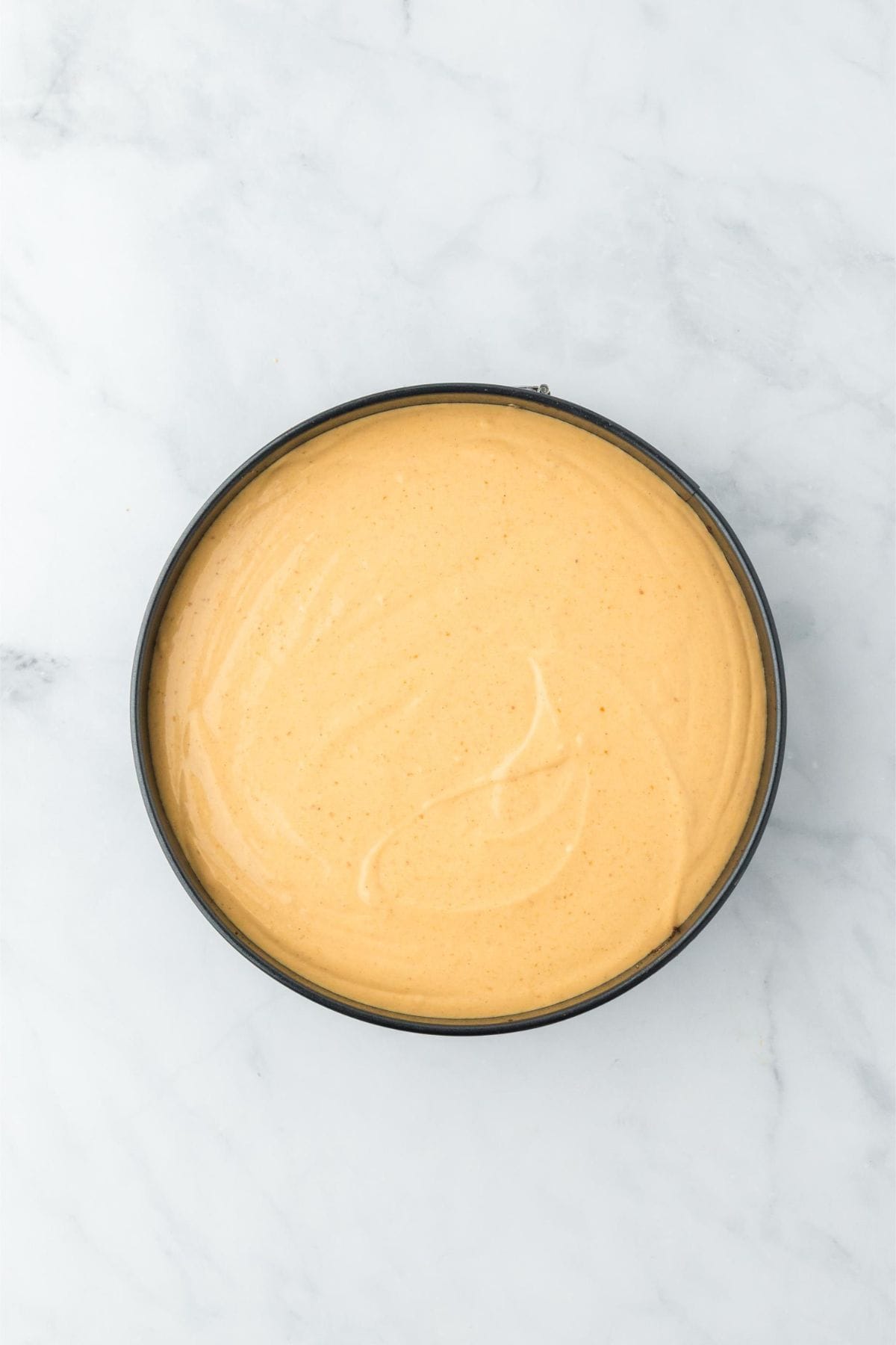 Pumpkin cheesecake filling evenly spread in the springform pan before baking