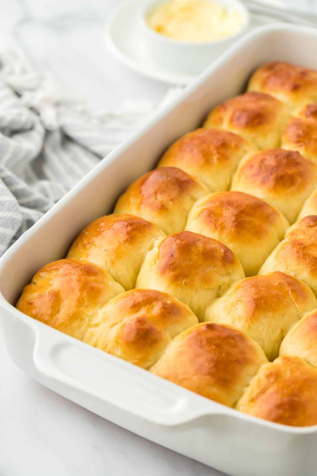 Yeast rolls in a white baking dish, with melted butter visible on top, ready to be served