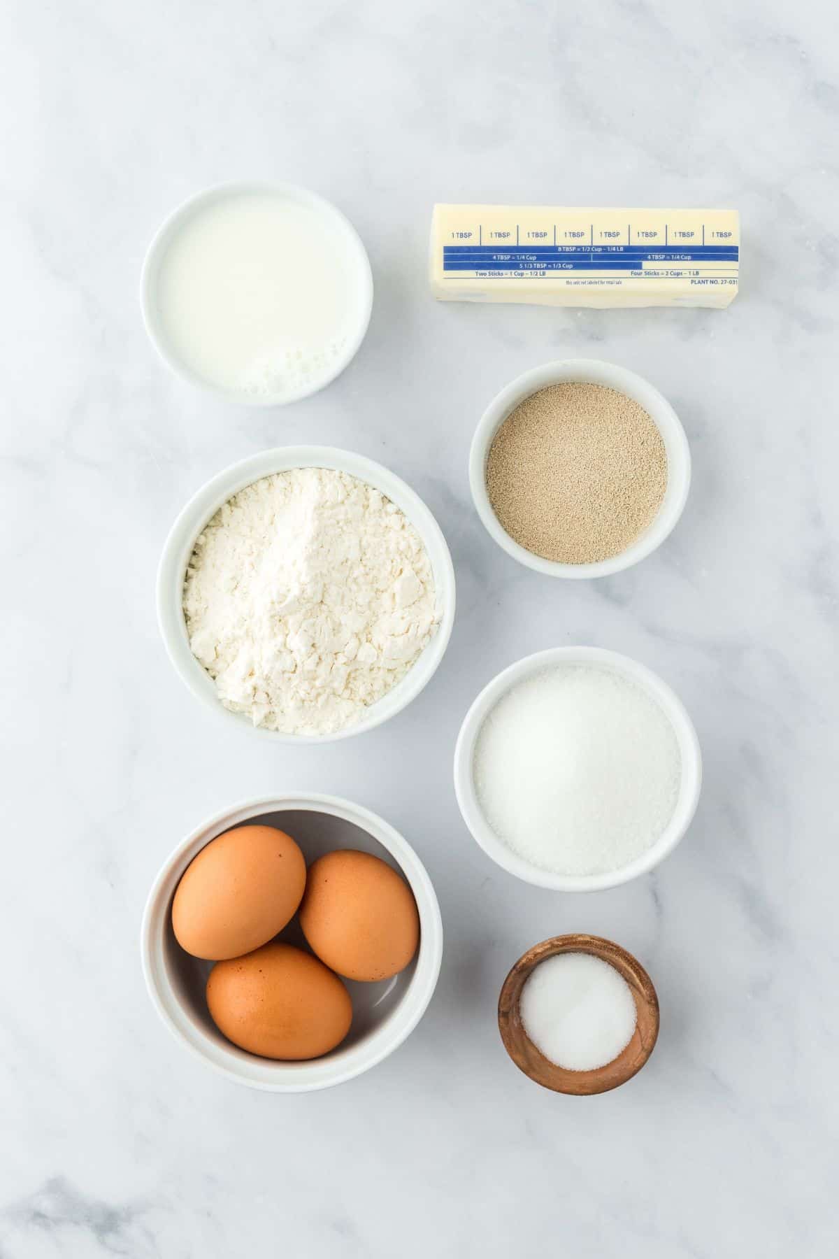 Overhead shot of ingredients for making yeast rolls on a marble surface before mixing