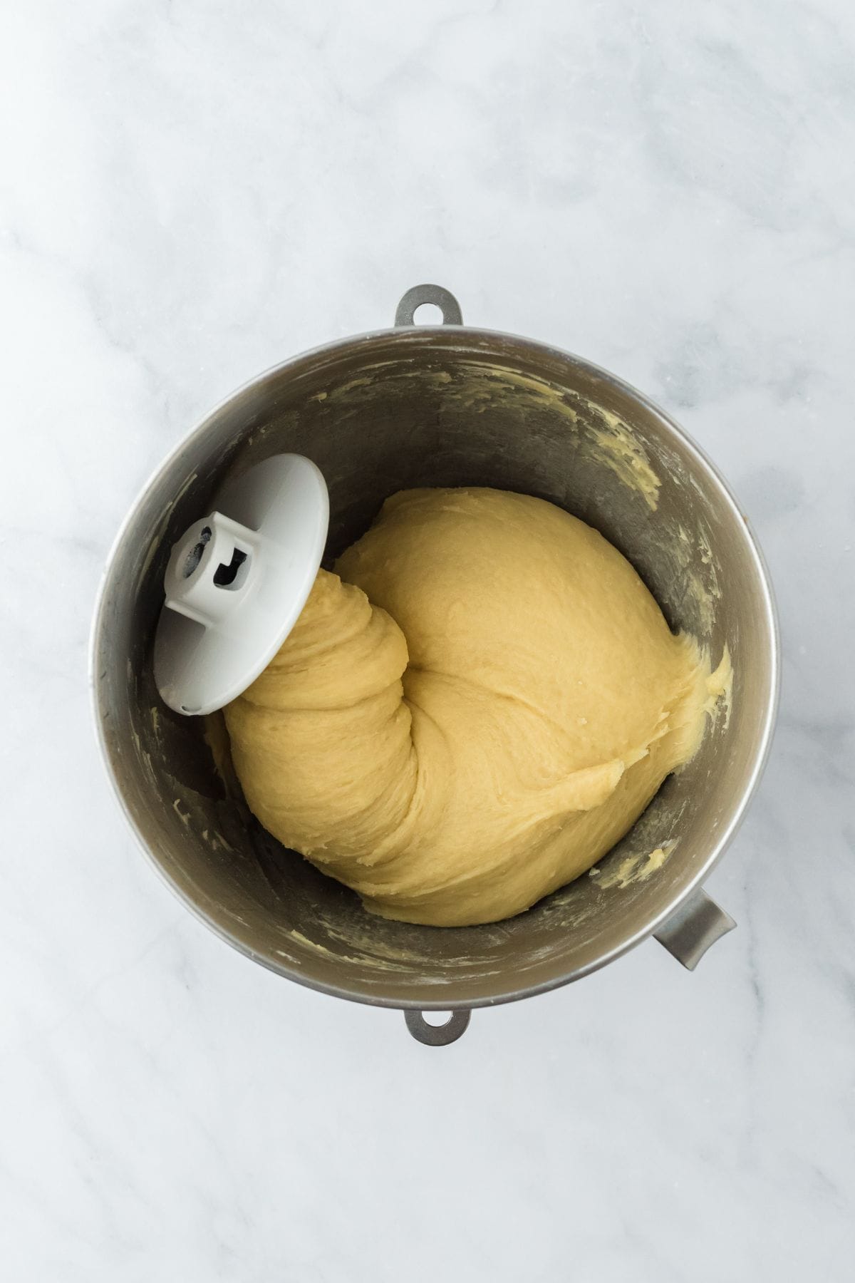 Smooth, elastic dough wrapped around a dough hook in the metal mixing bowl