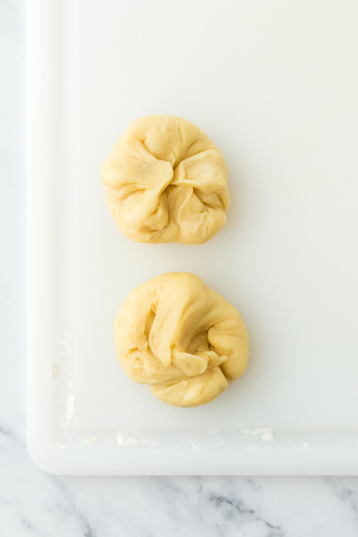 Two dough pieces shaped into knots on a cutting board