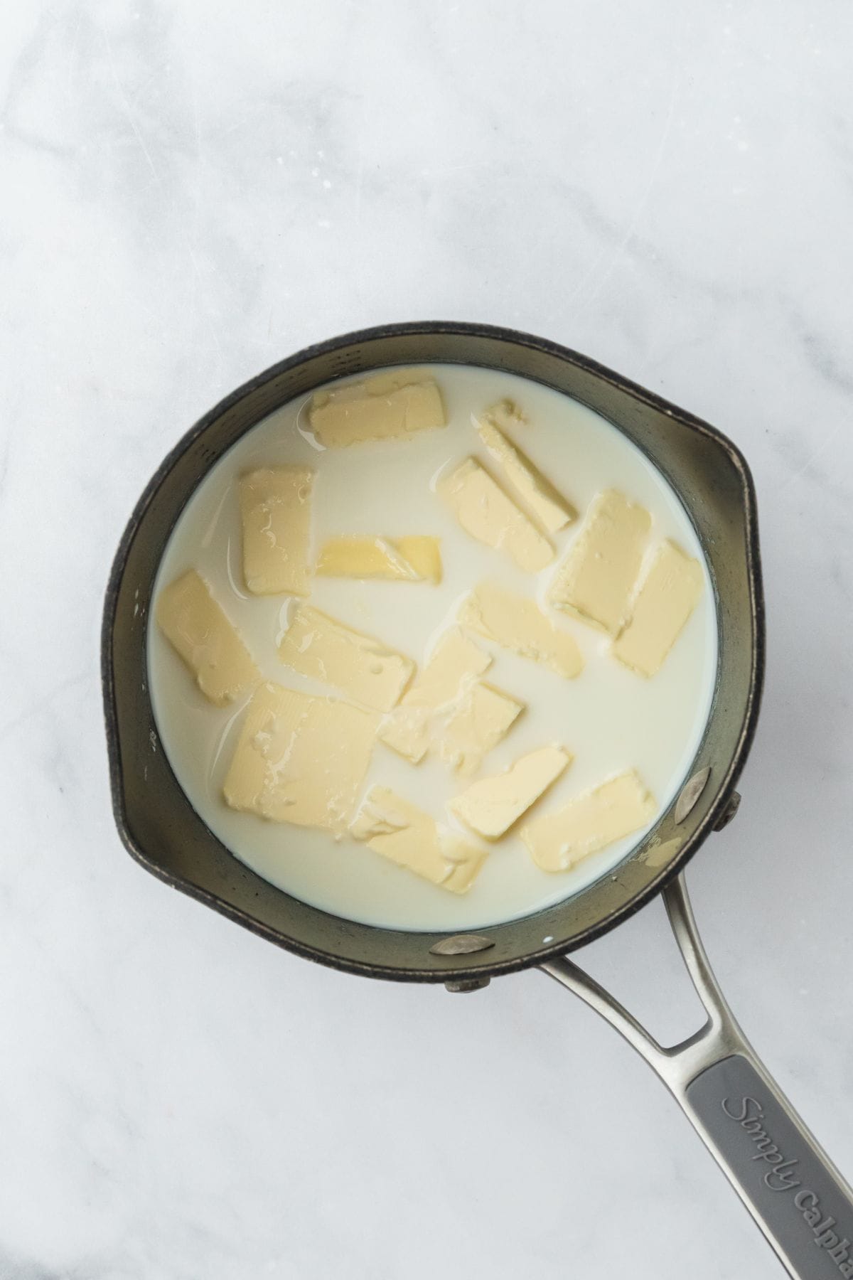 Butter melting into milk in a saucepan