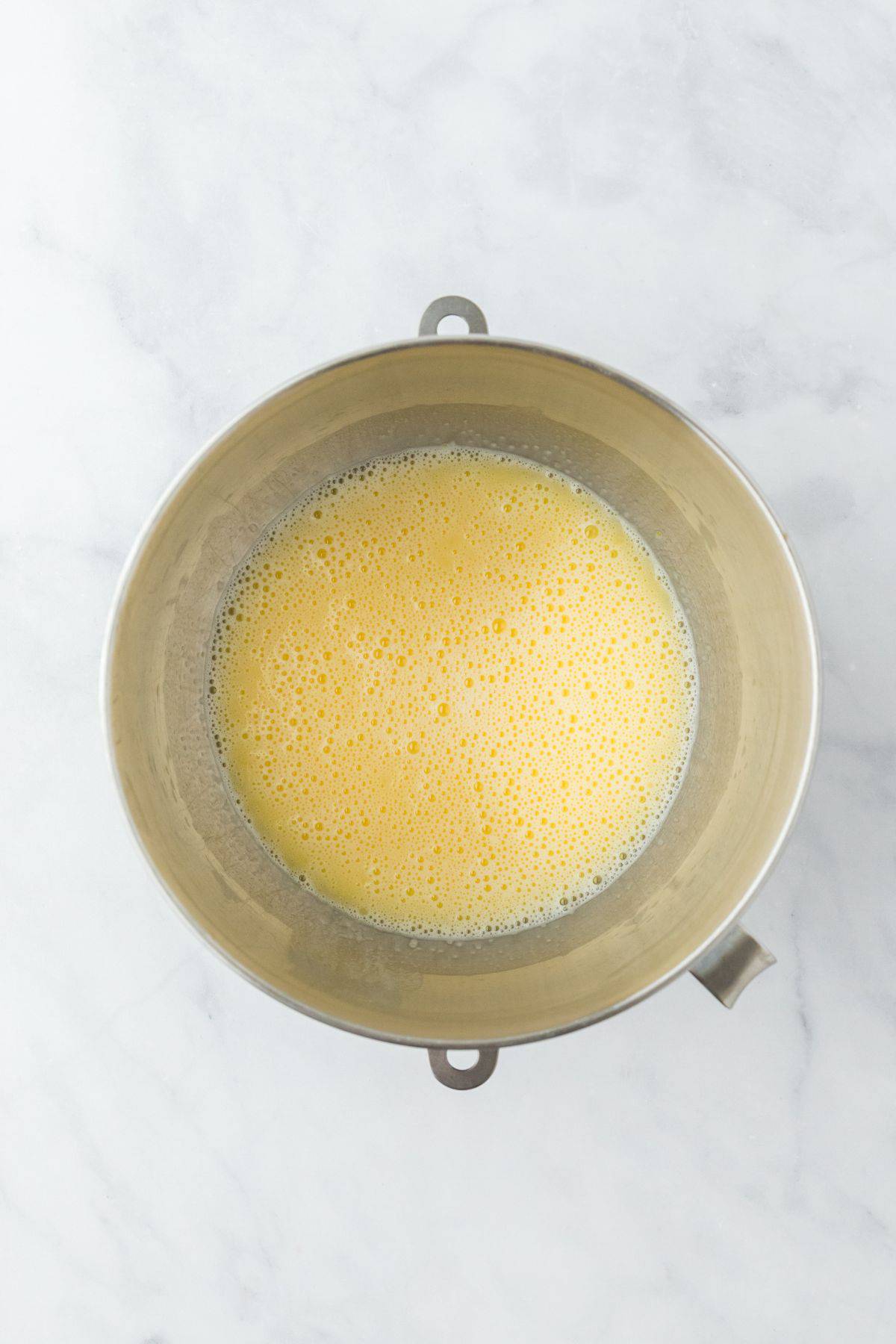 The egg mixture in the metal bowl, beaten until foamy