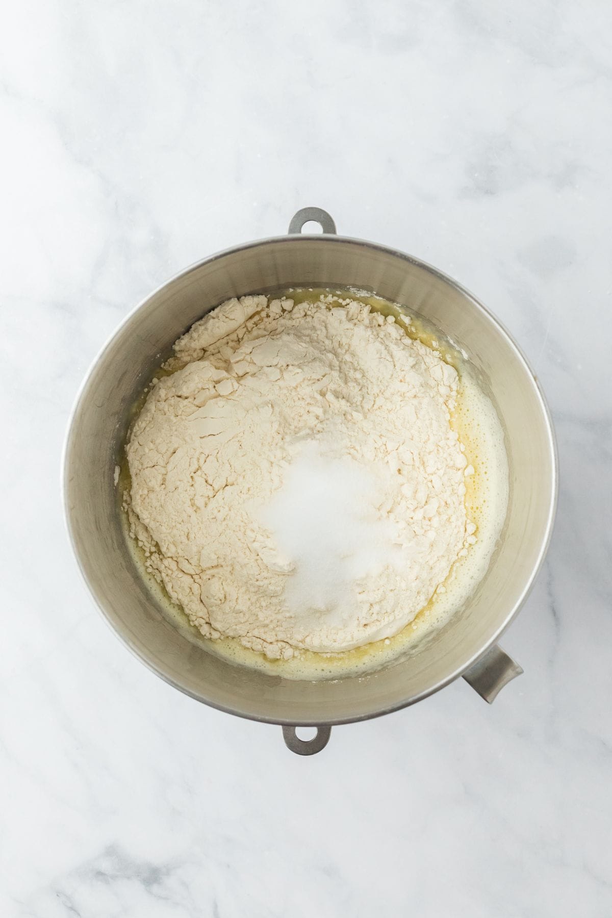 Flour and salt added to the egg mixture in a metal mixing bowl