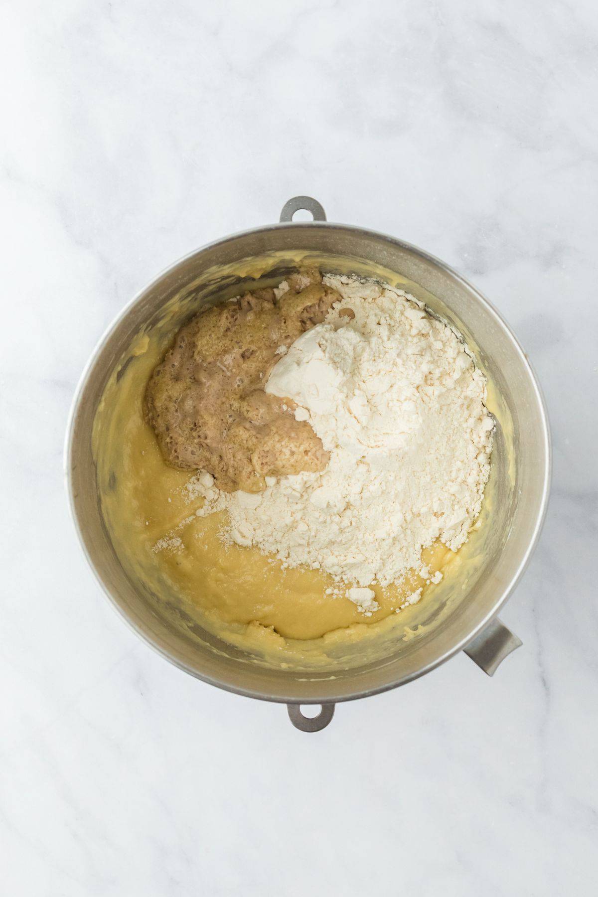 A metal bowl with the dough forming as yeast and flour are mixed with the egg mixture