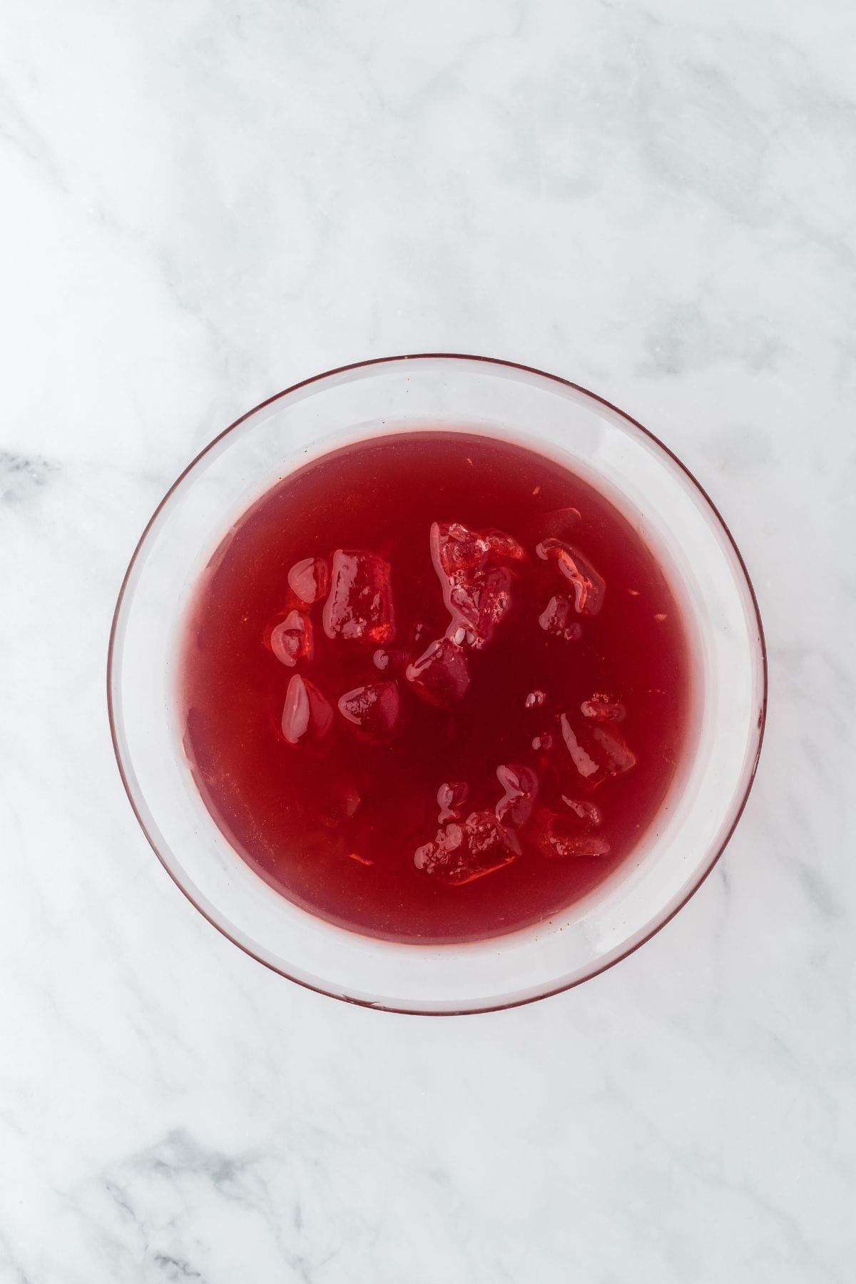 Overhead shot of a bowl filled with bright red Thanksgiving punch and ice cubes