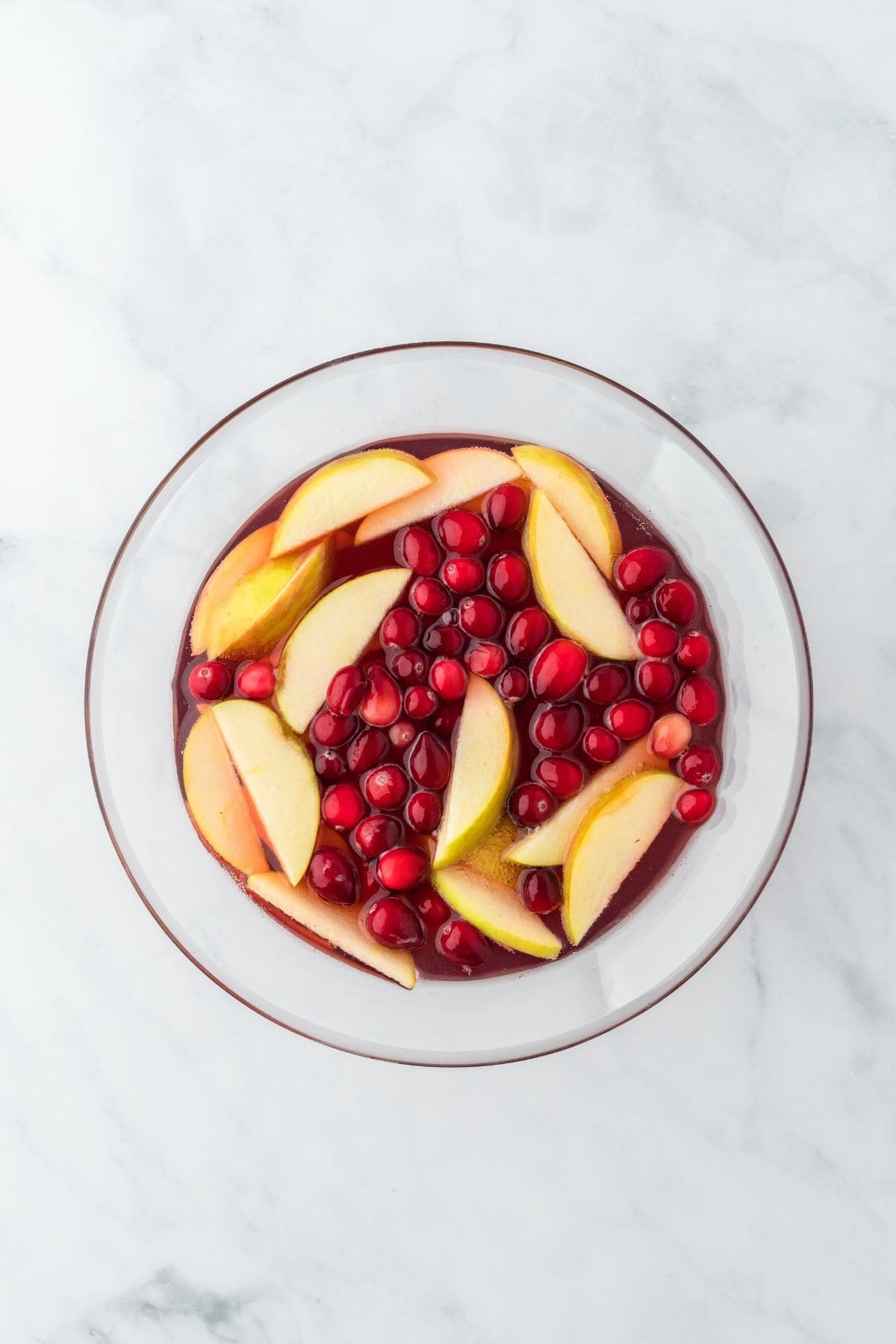 Overhead shot of a bowl of Thanksgiving punch with fresh apple slices and cranberries floating on top