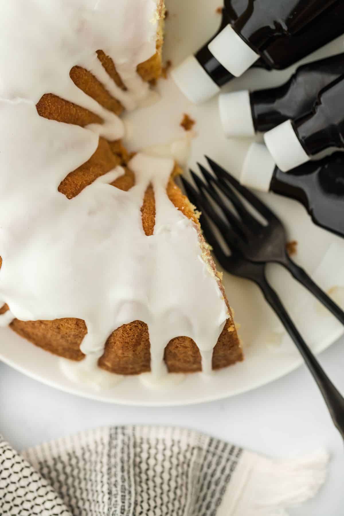 Overhead shot of five flavor pound cake with white icing, next to several forks and bottles