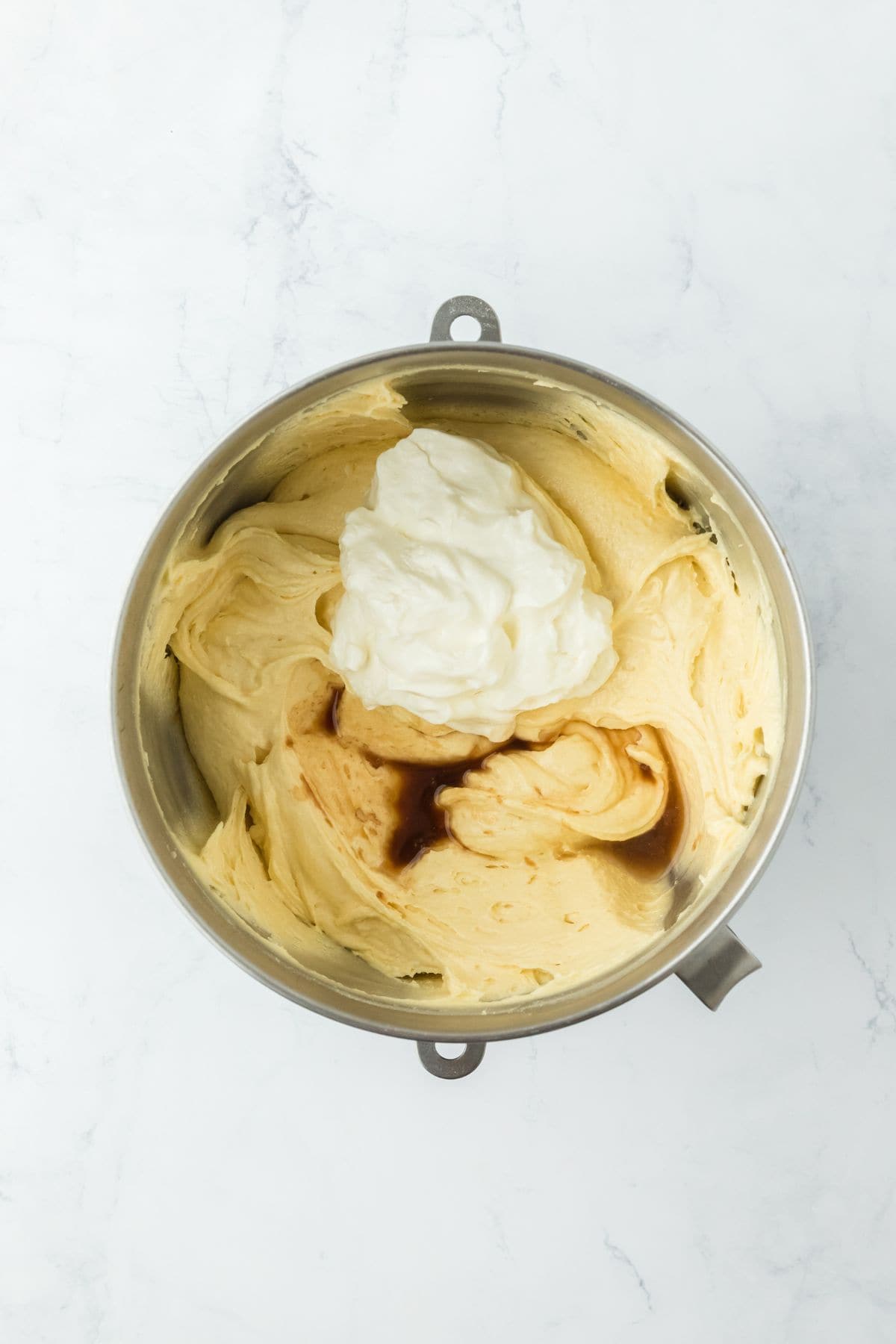 A mixing bowl with thick batter and a dollop of sour cream and vanilla extract added