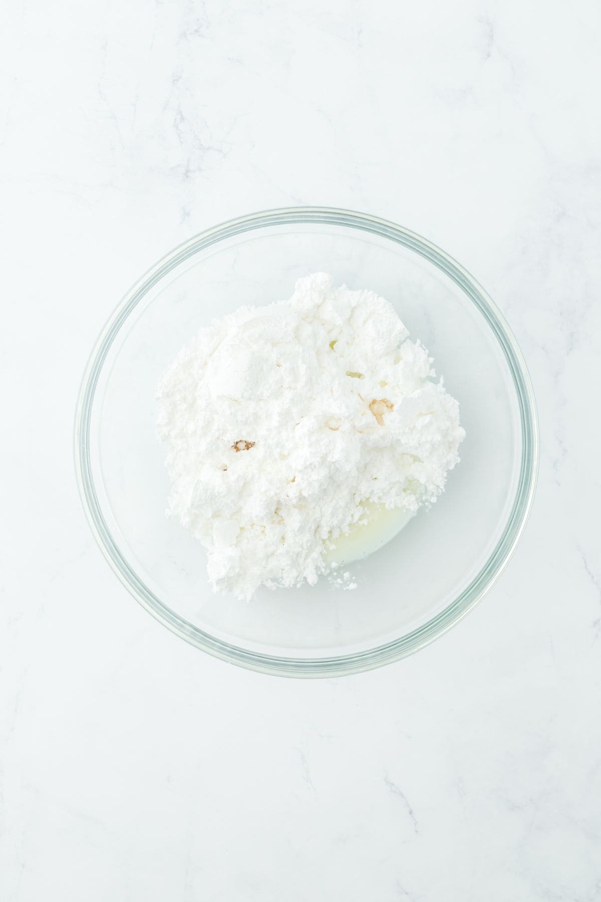 A bowl of powdered sugar, milk and extracts ready for mixing