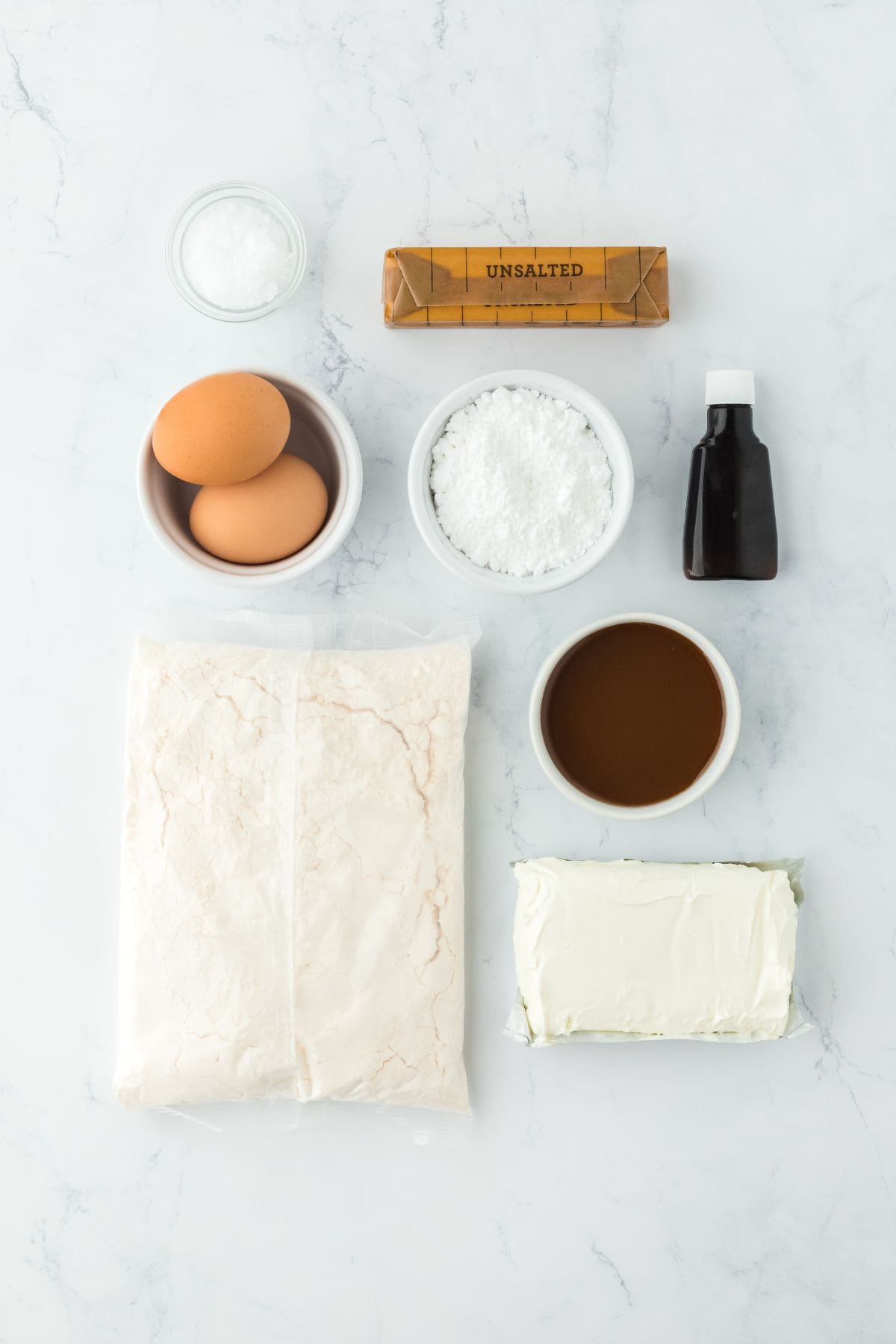 Overhead shot of ingredients for making gooey brown butter cake on a white surface before mixing