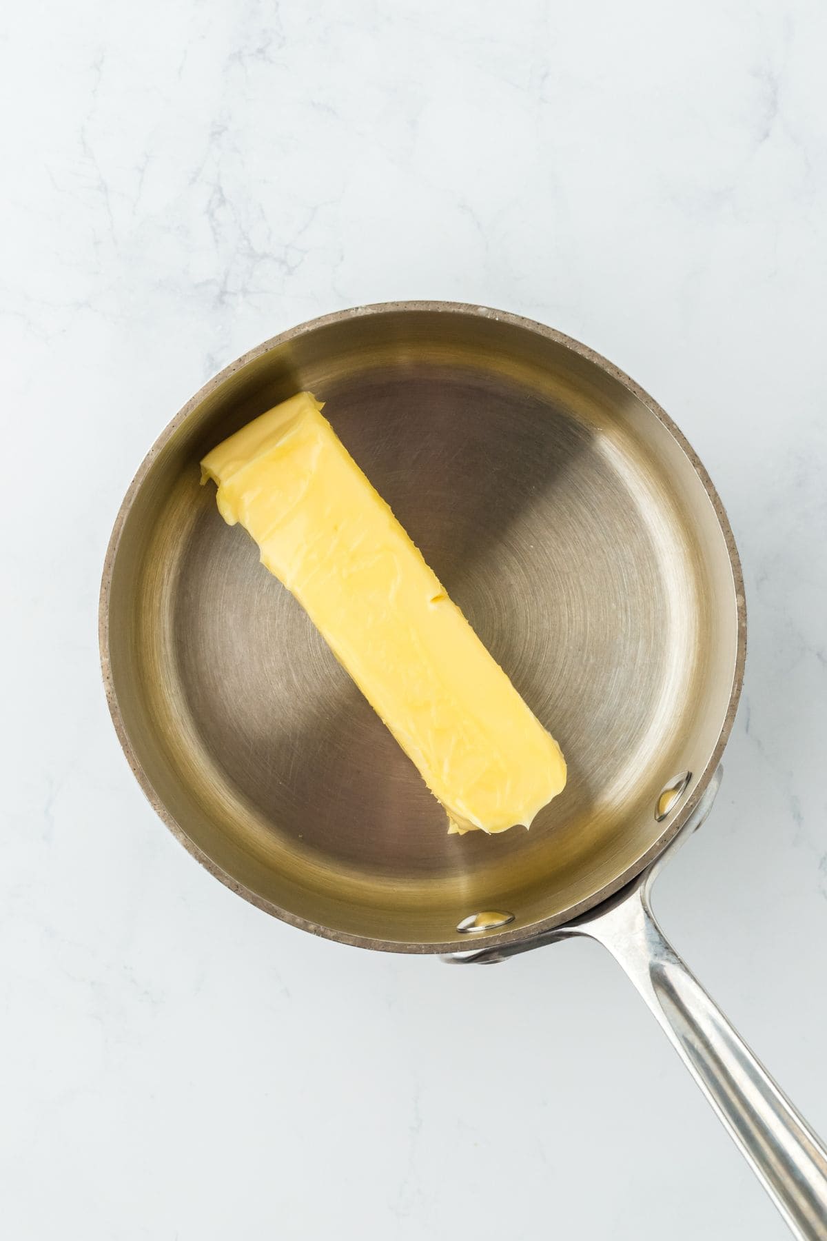 A stick of butter in a metal pan, about to be melted