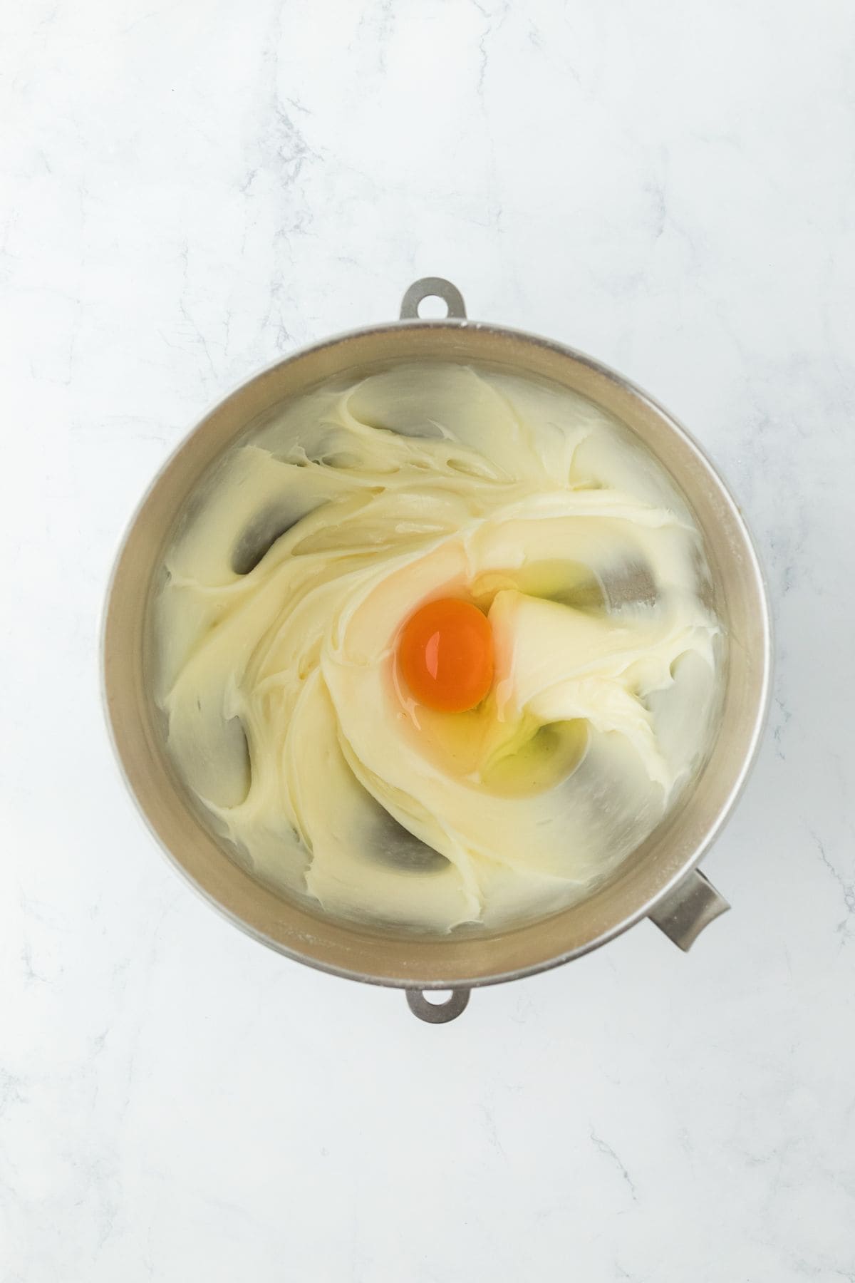 An egg on top of whipped cream cheese mixture, ready to be incorporated