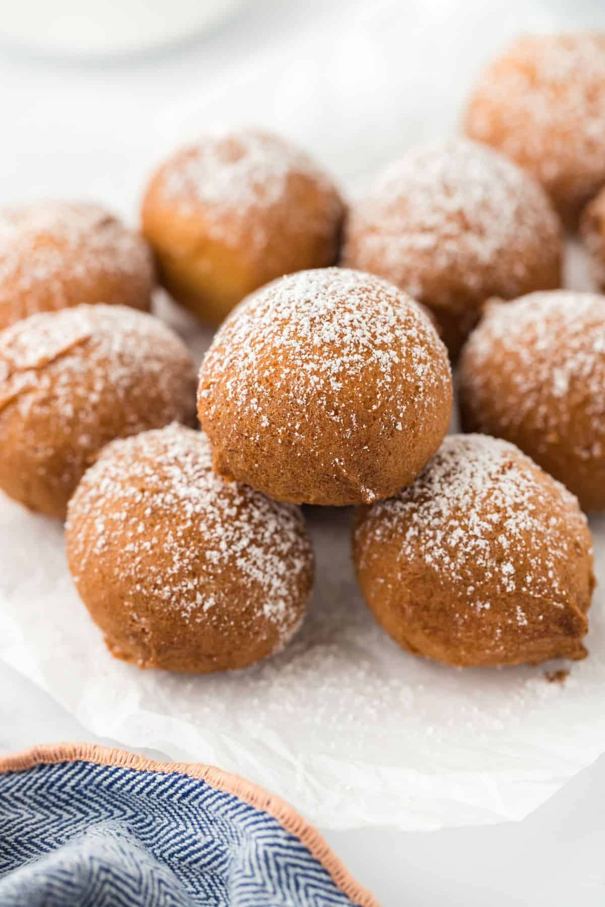 A batch of freshly made pound cake beignets arranged on a plate, lightly sprinkled with powdered sugar