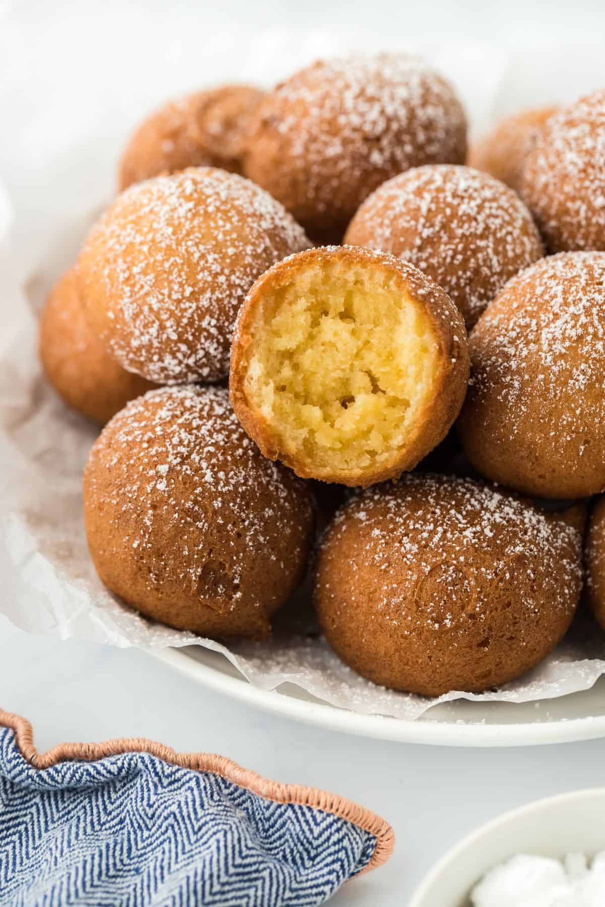 A closeup of a pile of pound cake beignets with a soft, moist interior showing in one