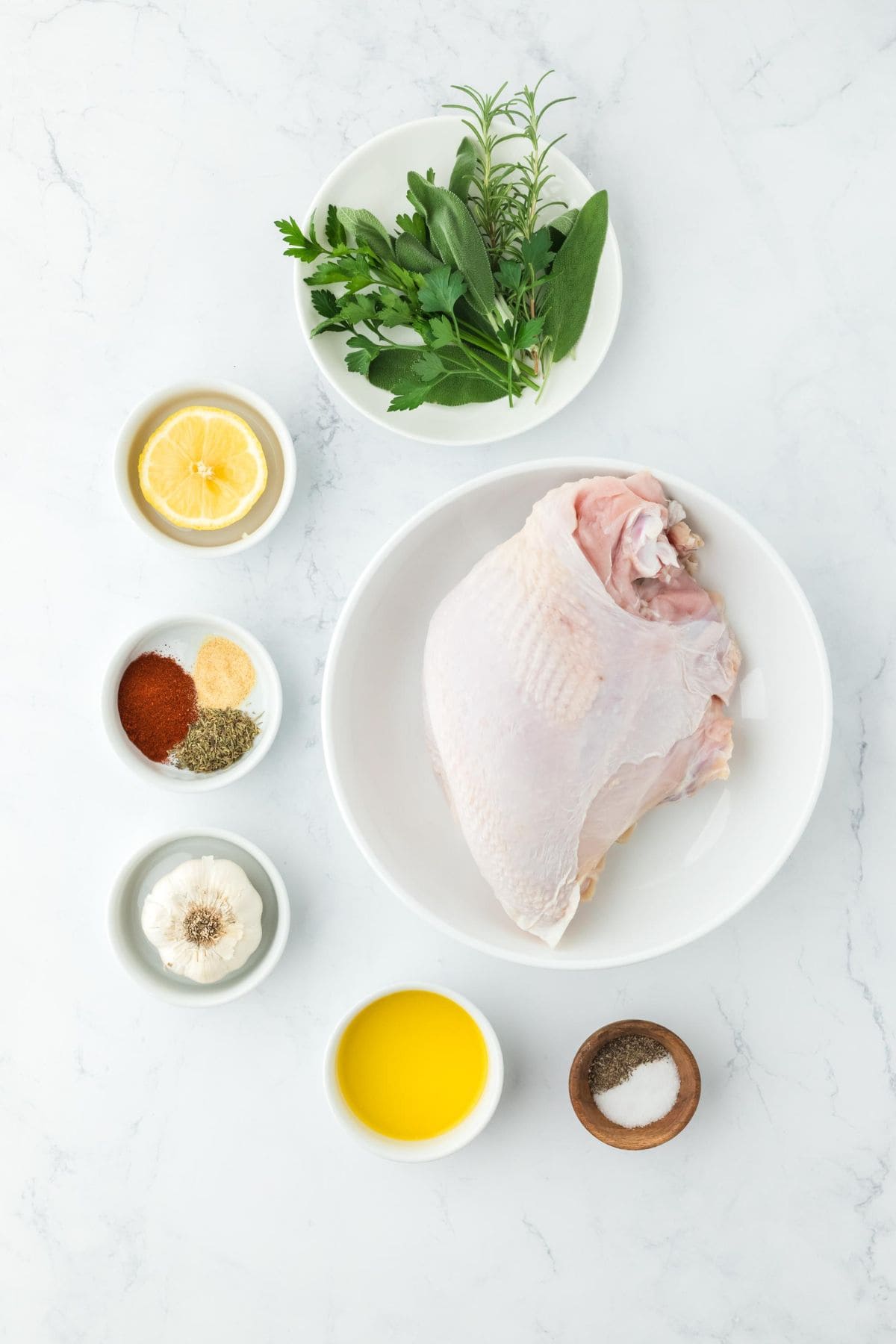 Overhead shot of ingredients to make roasted turkey breast on a white surface before roasting