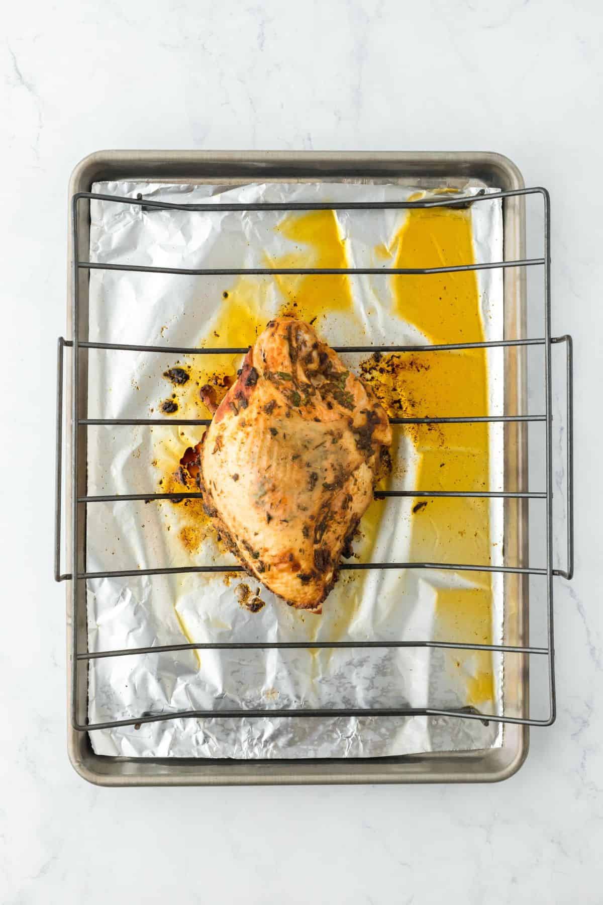 Roasted turkey breast, showing golden juices on the foil-lined baking sheet