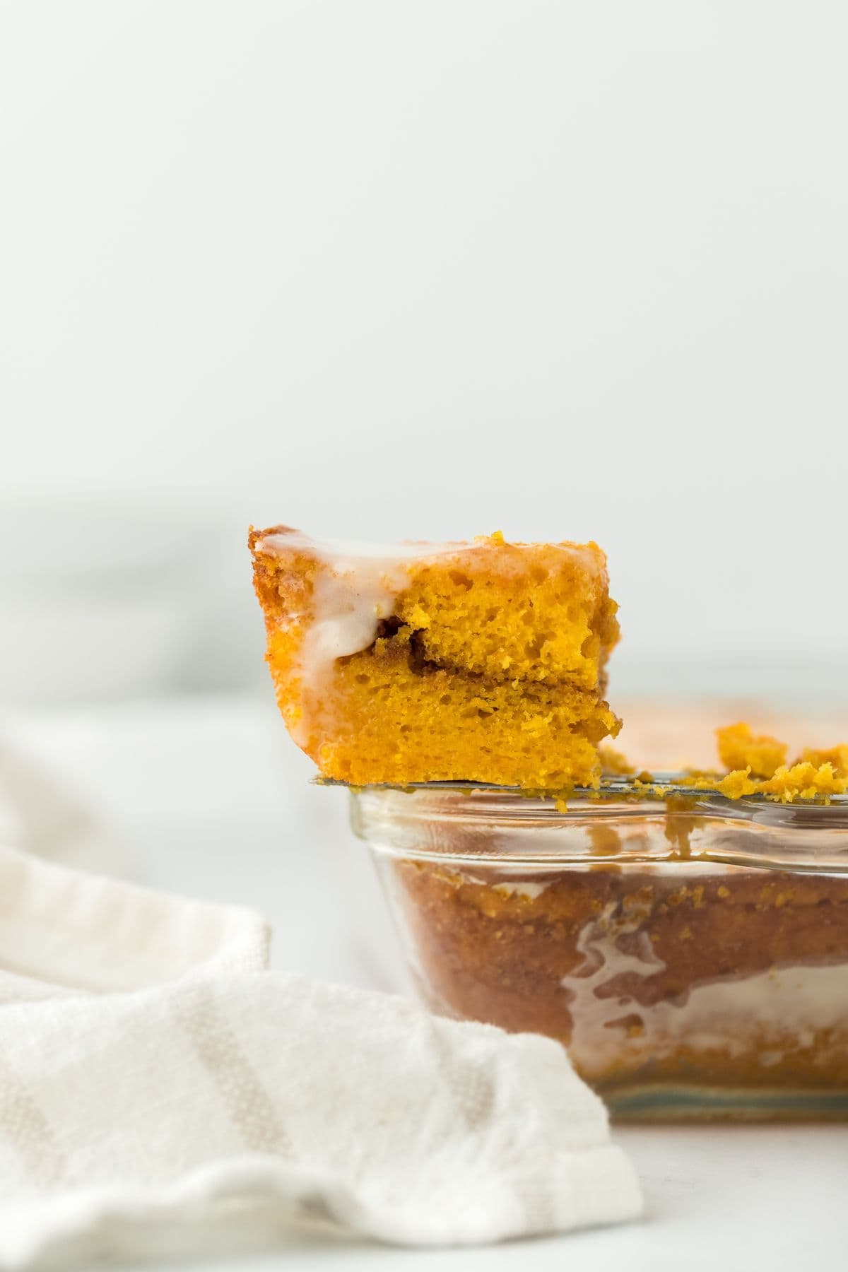 A single slice of Sweet Potato Honey Bun Cake lifted out of the baking dish