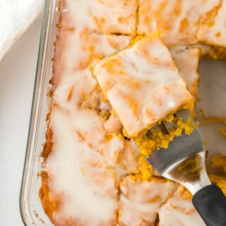 Sweet Potato Honey Bun Cake in a glass baking dish, sliced into squares with one piece being served on a spatula