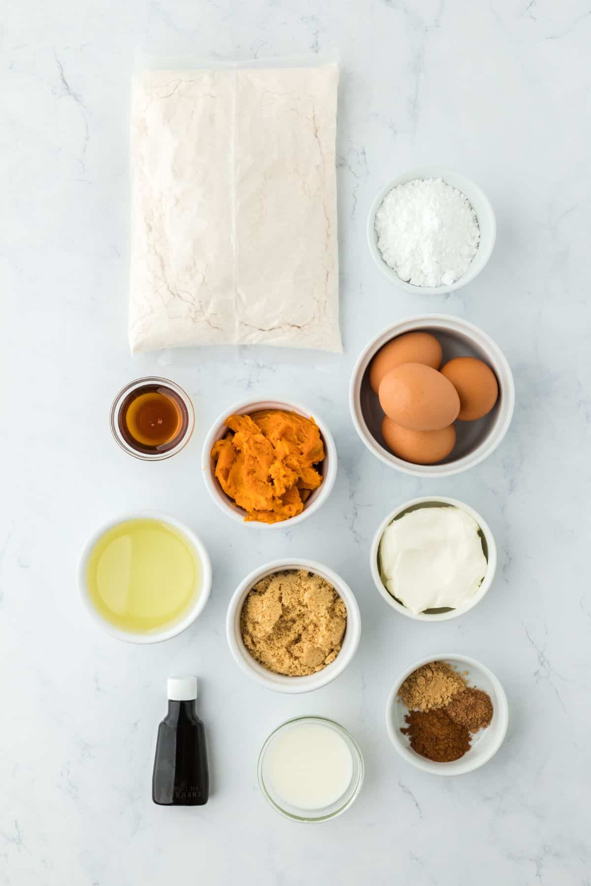 Overhead shot of ingredients for making sweet potato honey bun cake on a marble surface before baking