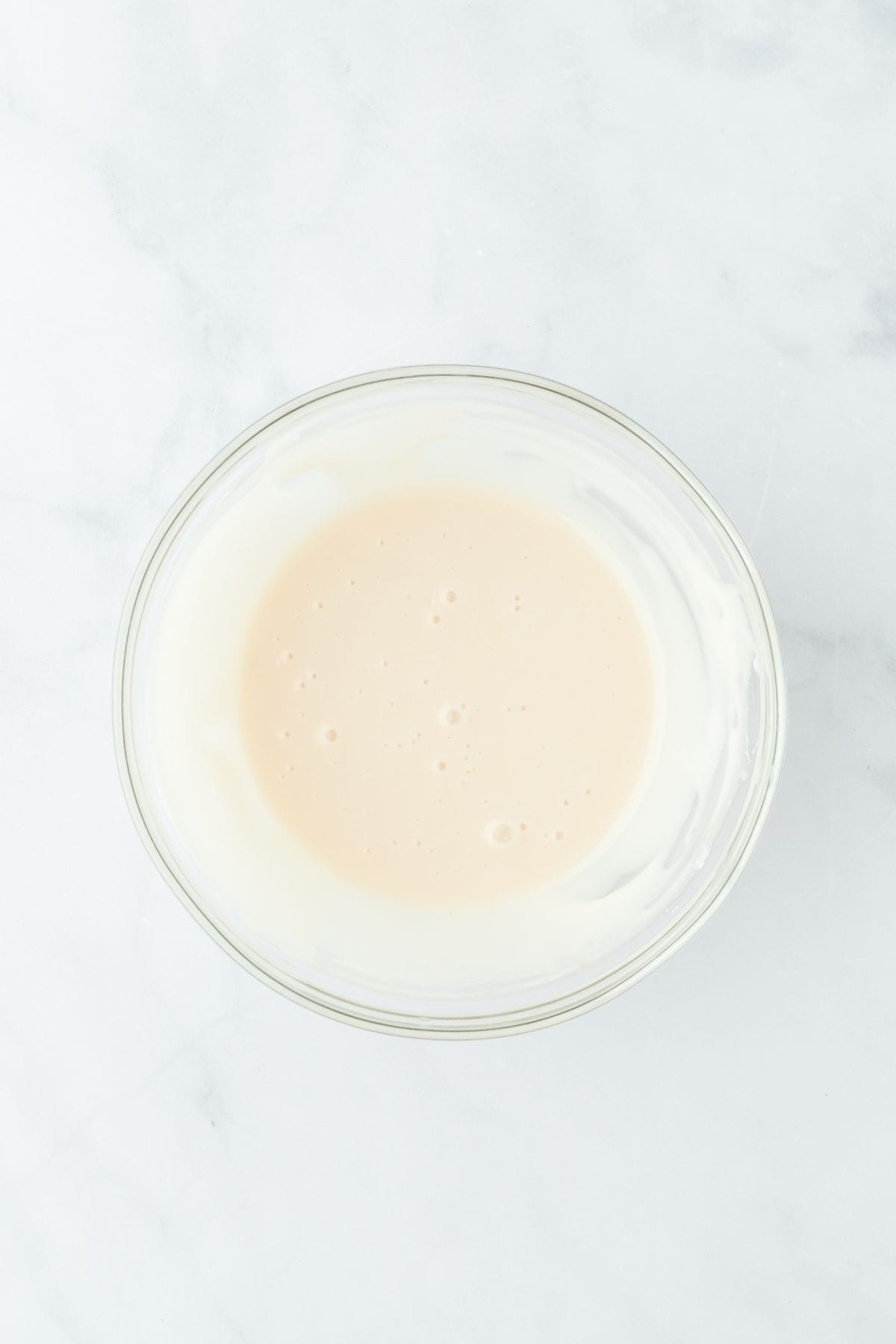 Mixed icing in a glass bowl, smooth and ready to be poured