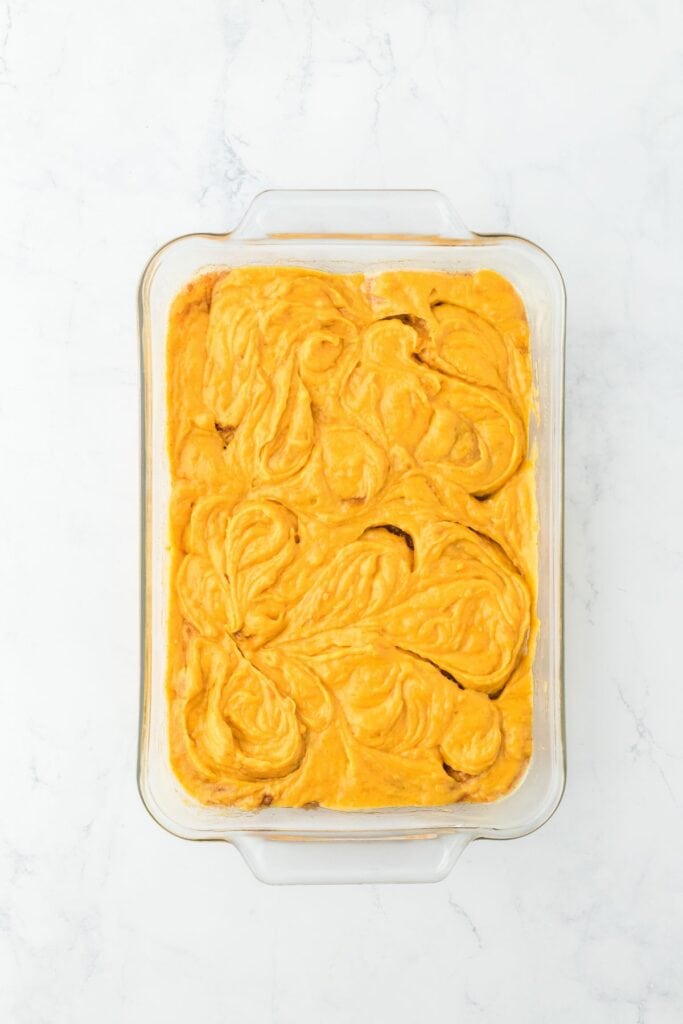 The cake batter swirled with a knife to incorporate the spice layer in the glass dish