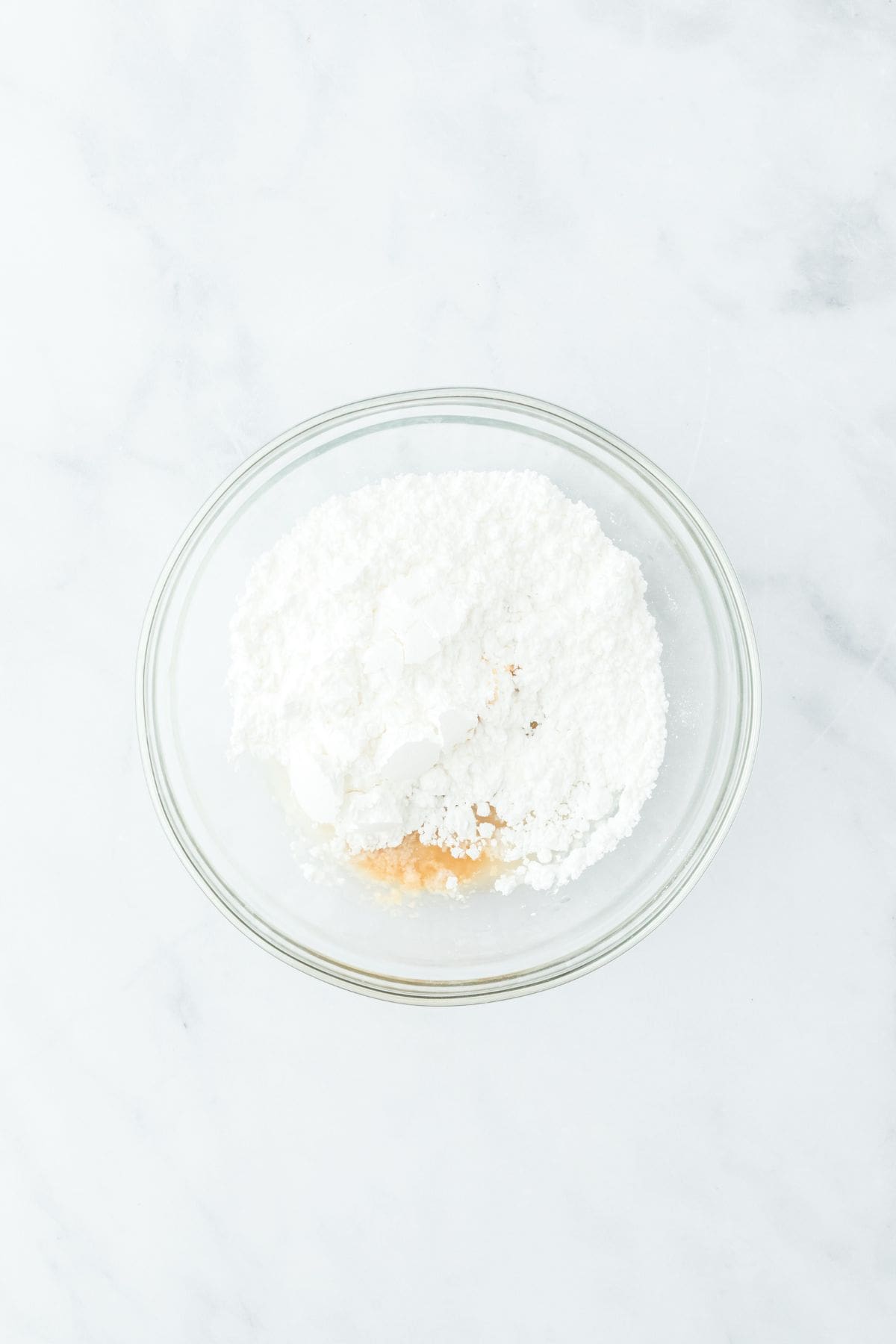 Ingredients for the icing added to a glass bowl