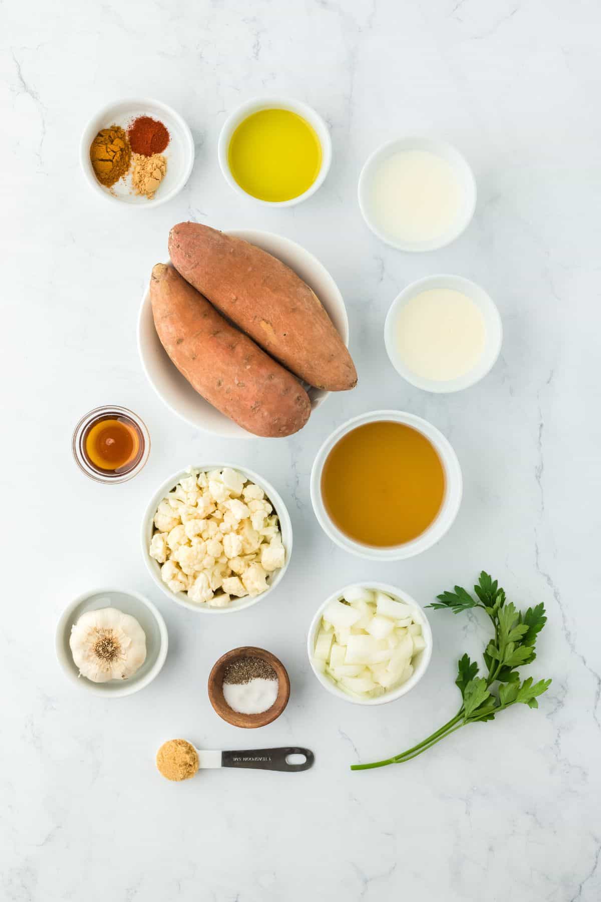 Overhead shot of ingredients for making sweet potato soup on a marble surface before cooking