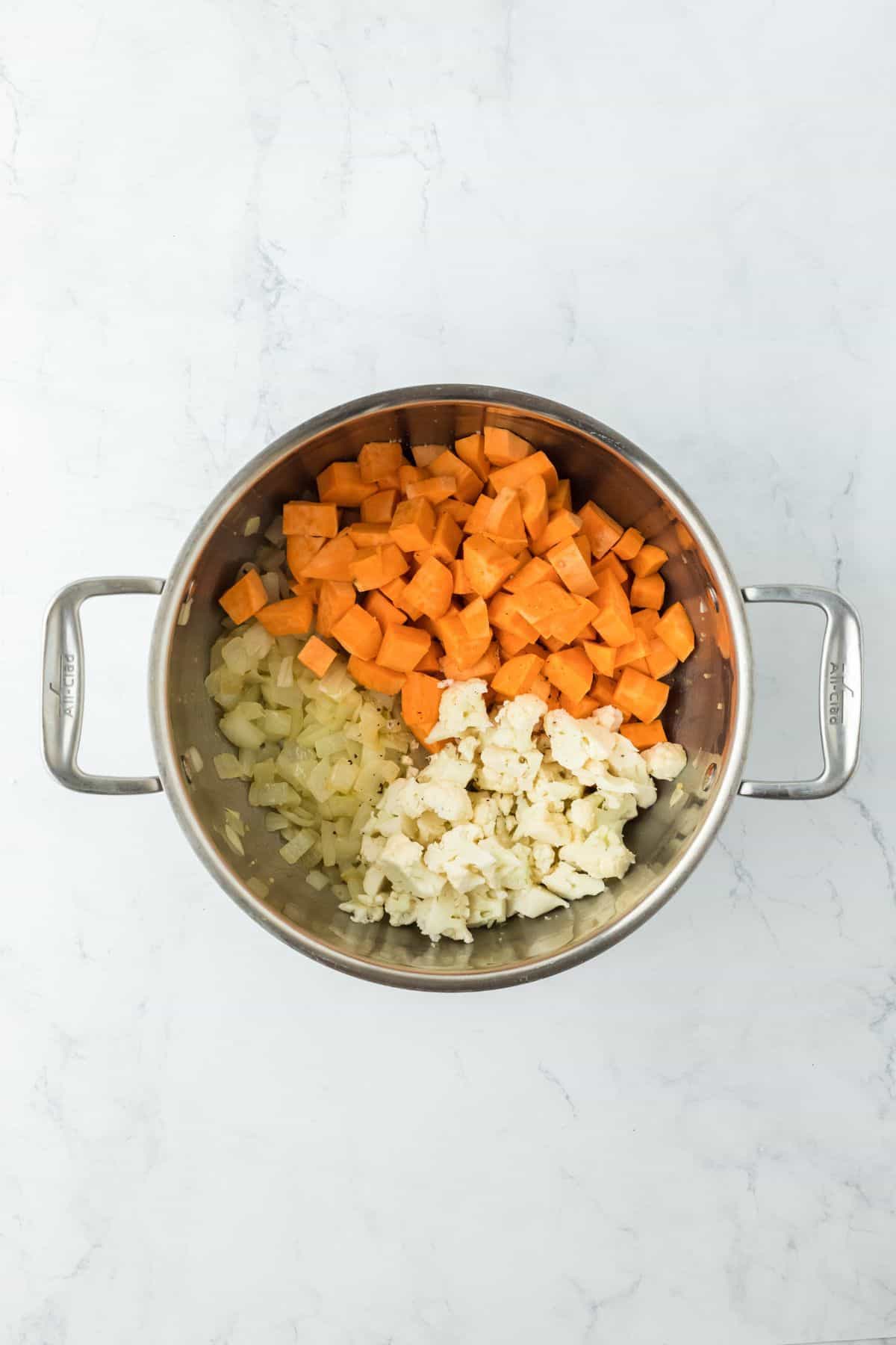 Cubed sweet potatoes and cauliflower florets added to the sautéed onions and garlic in the pot