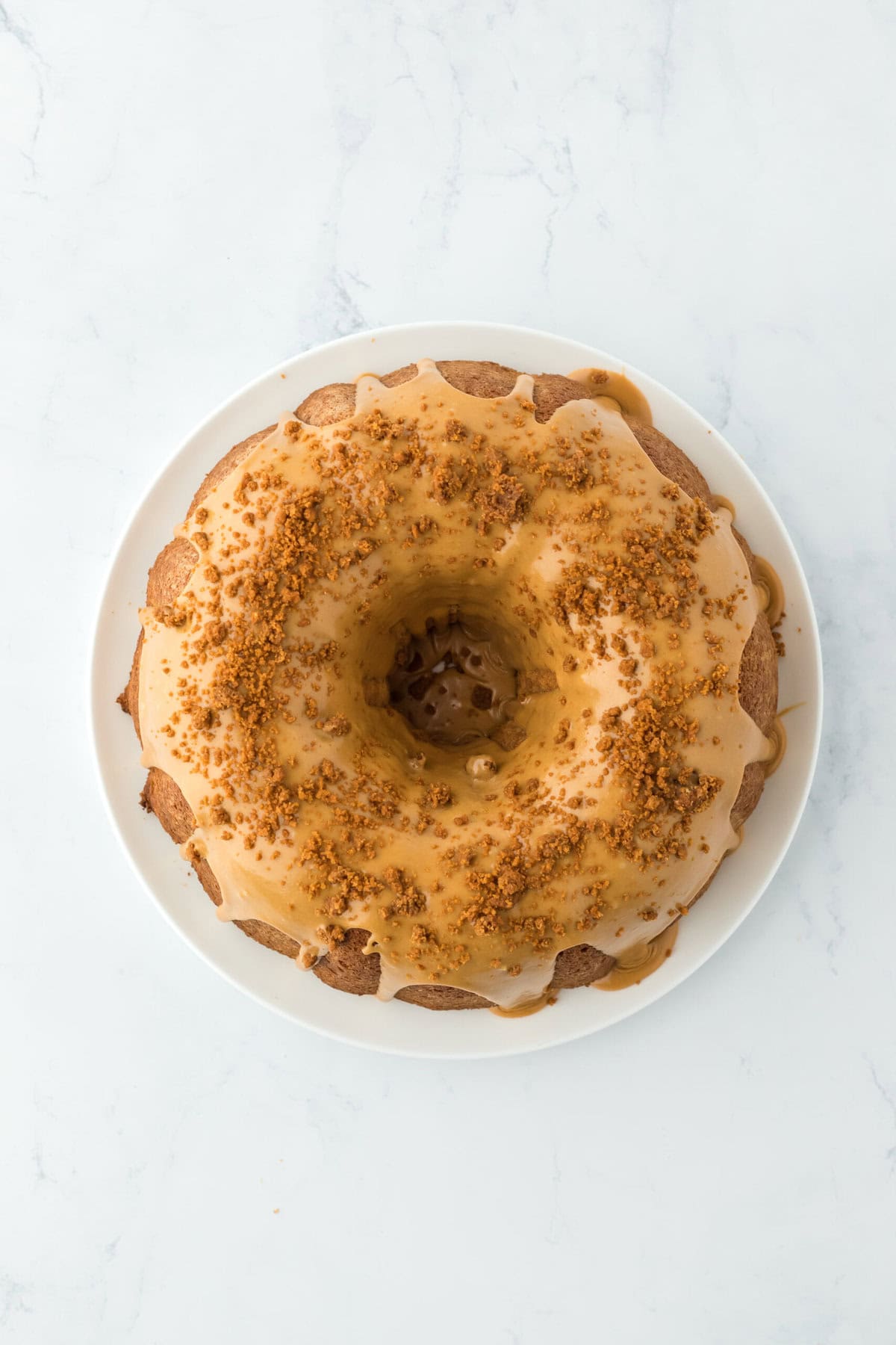 biscoff glaze over a biscoff cake sprinkled with crushed biscoff cookies