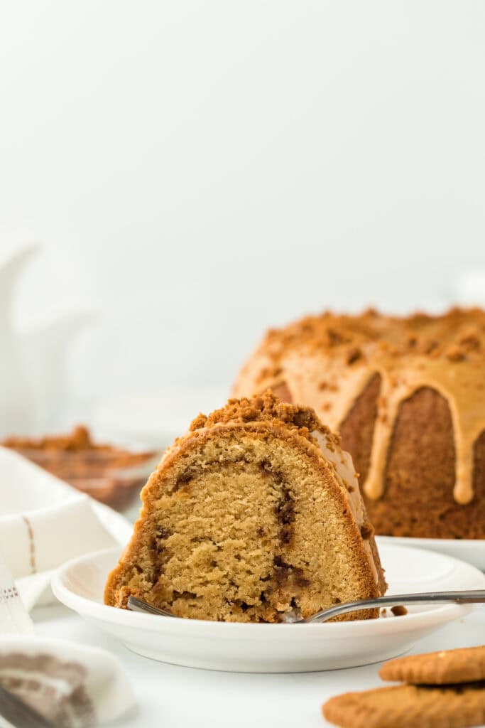 slice of biscoff cake with cookie butter glaze and cookie crumbles on top