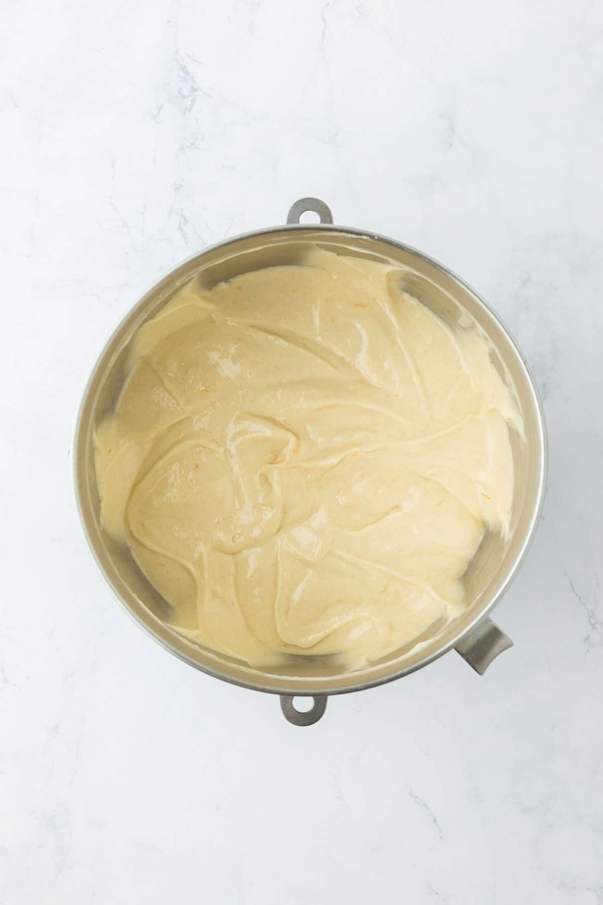 Smooth orange cake batter in a stand mixer bowl