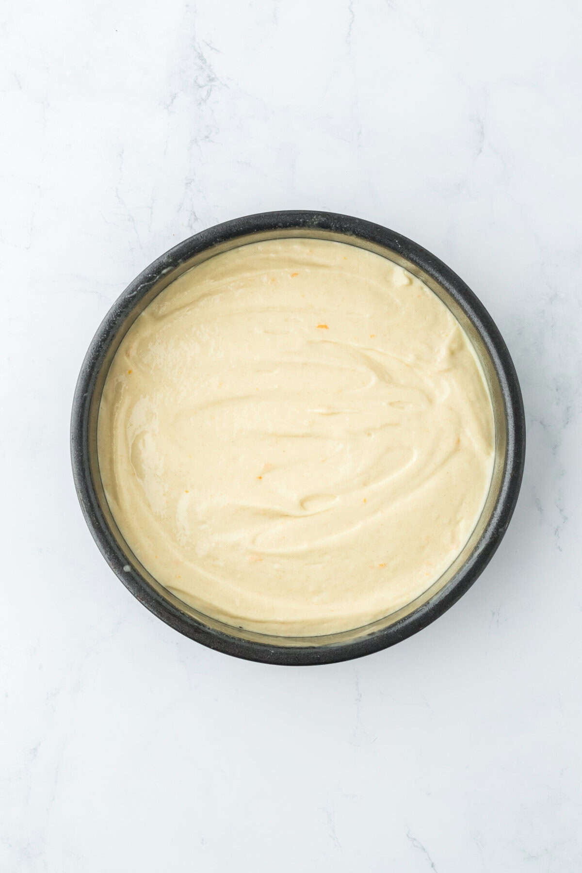 Cake batter in a cake pan on white countertop