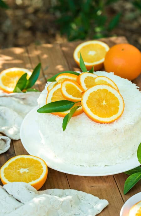 An orange coconut cake sitting on a wooden table outside before enjoying