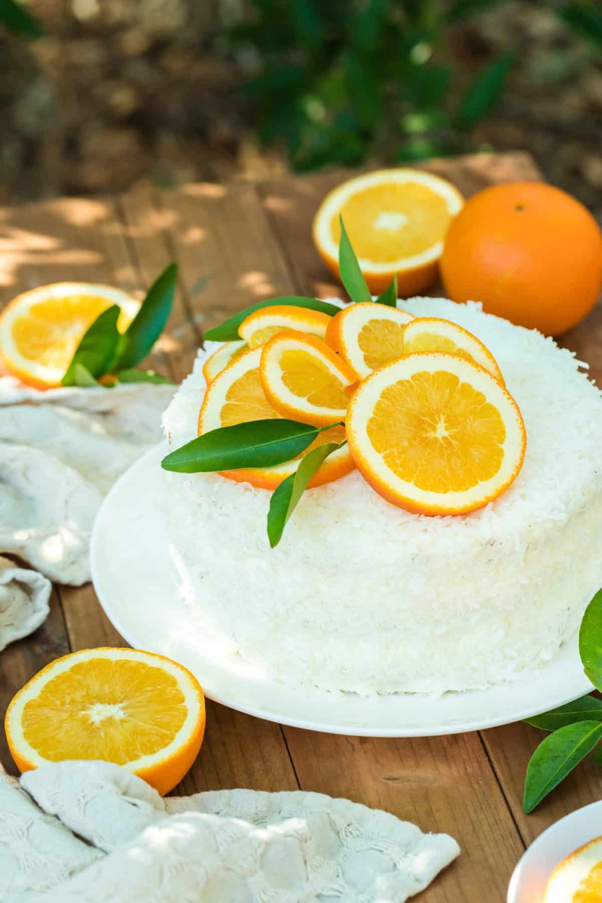 An orange coconut cake sitting on a wooden table outside before enjoying