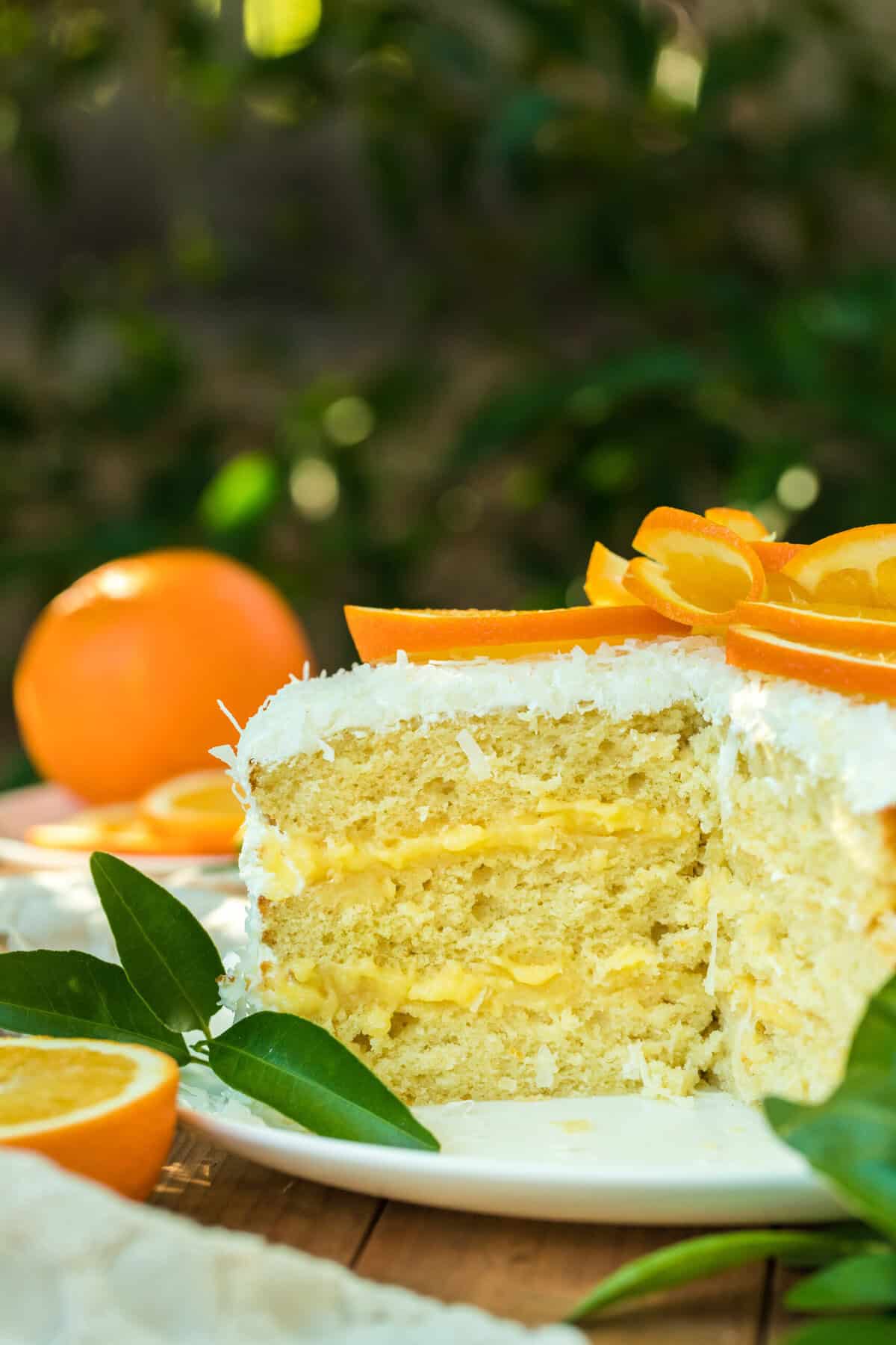 A coconut layer cake with orange filling sliced open on a wooden table