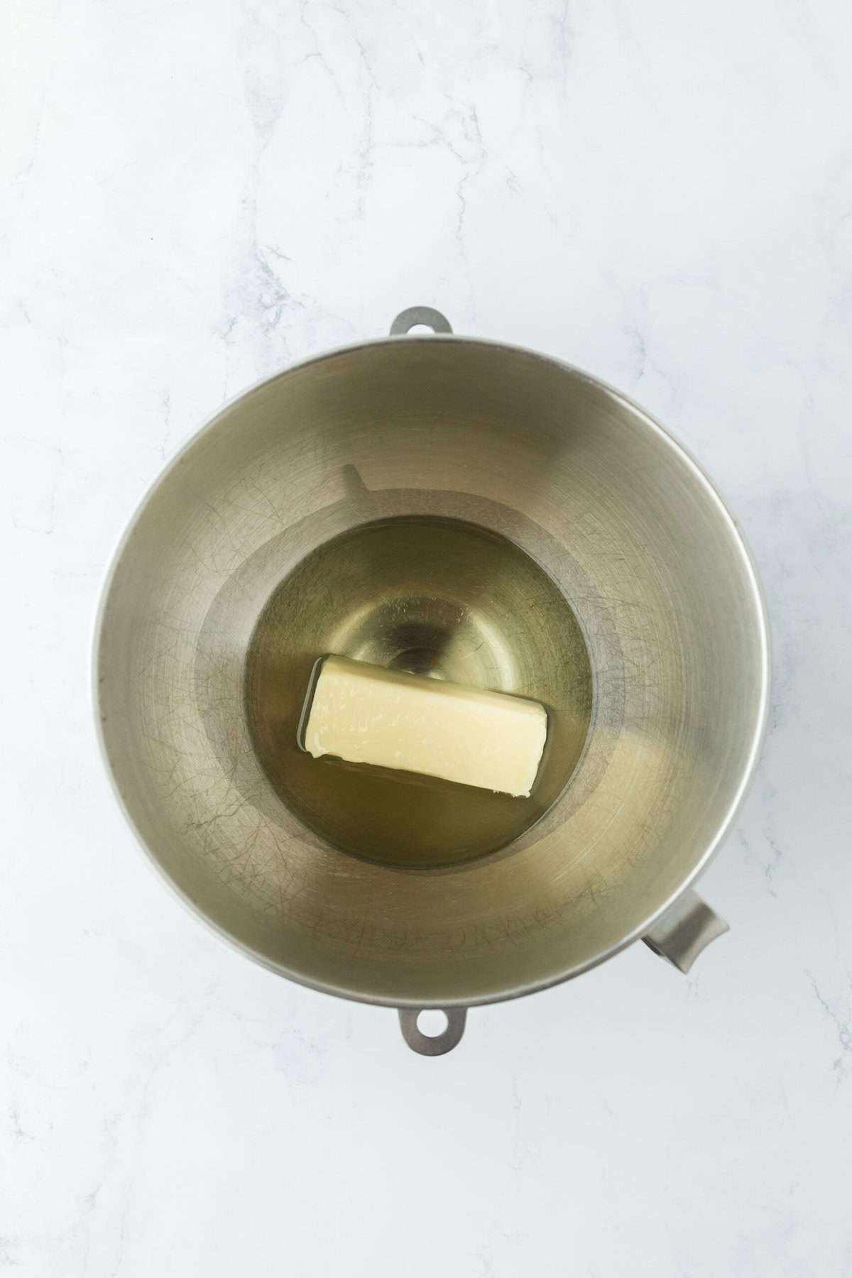 Butter and oil in a stand mixer bowl on white countertop