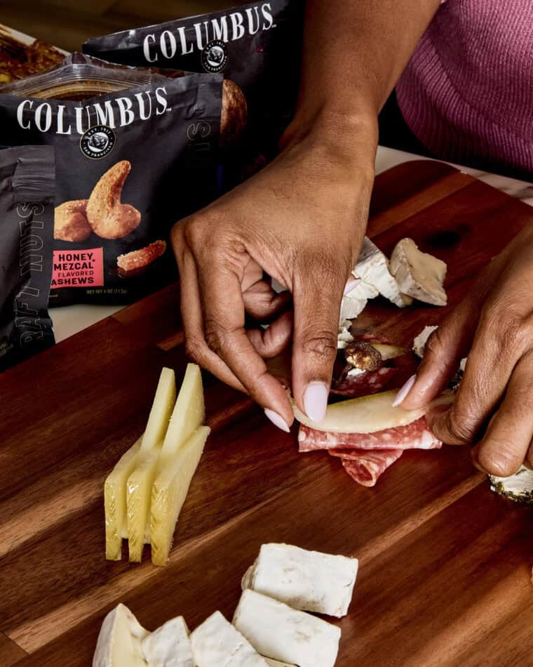 Jocelyn Delk Adams' hands building charcuterie bites on a Christmas tree board 