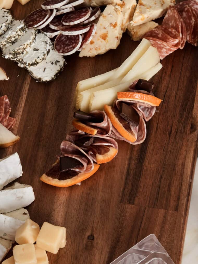 Charcuterie bites with blood orange being built on a board