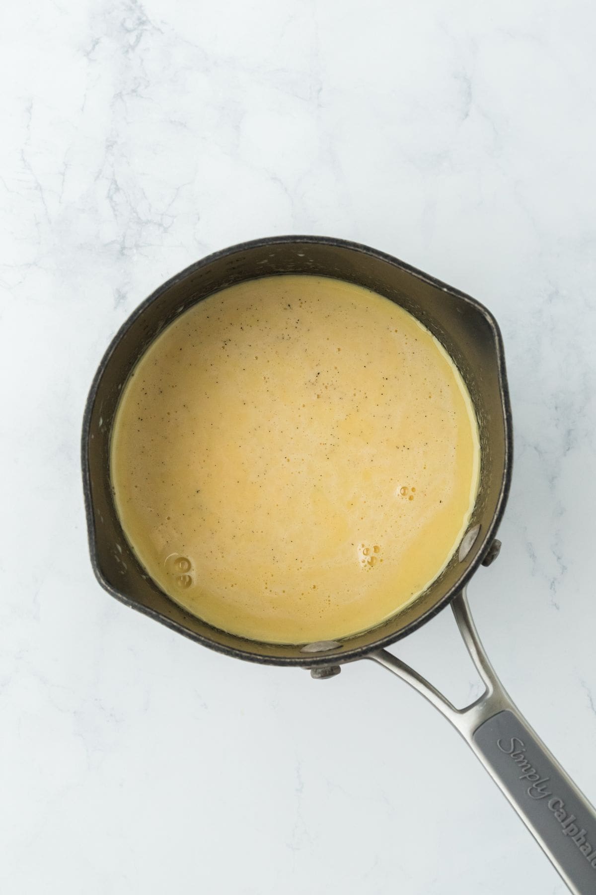 A saucepan with a custard-like mixture starting to thicken