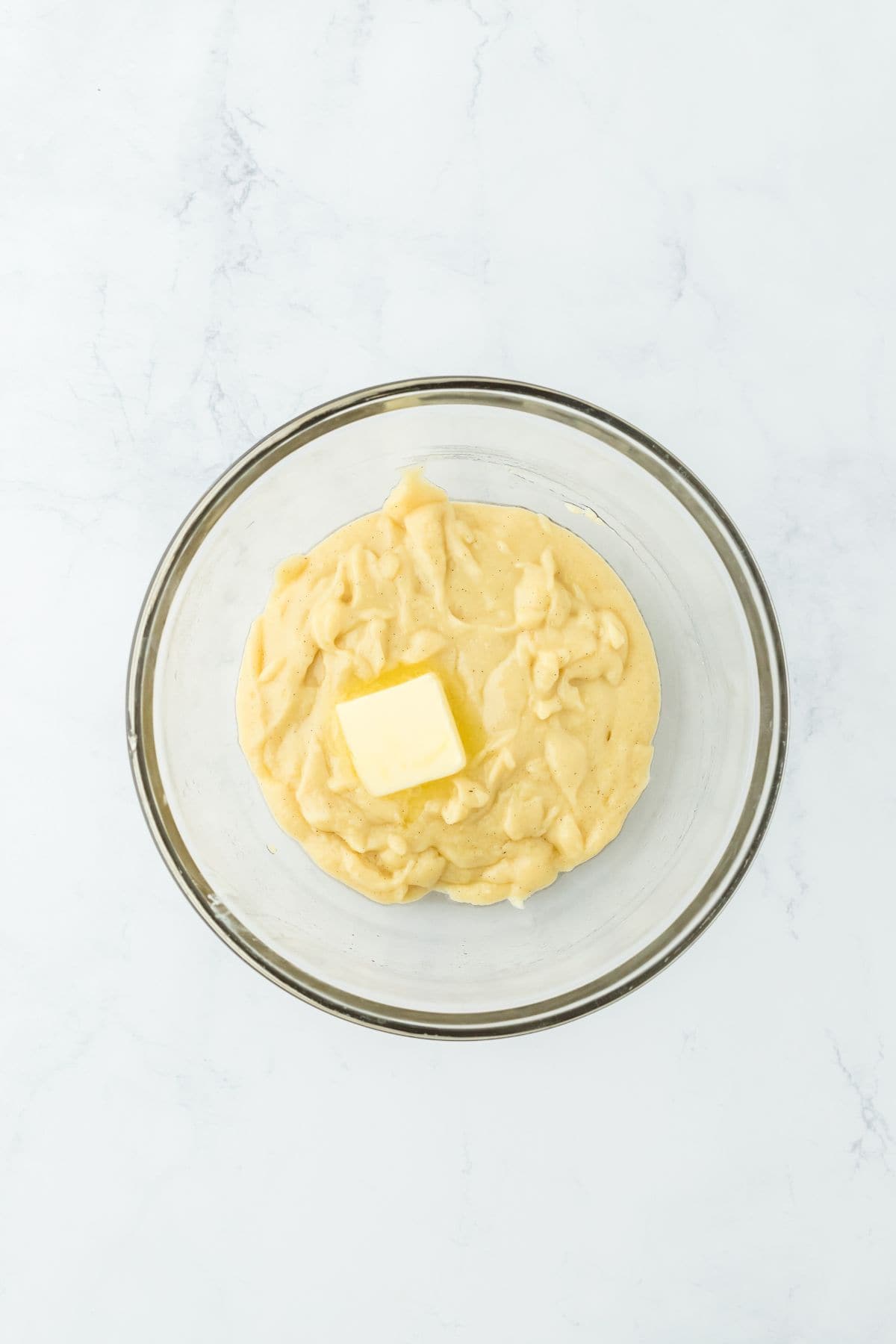 Custard mixture with a pat of butter in a glass bowl