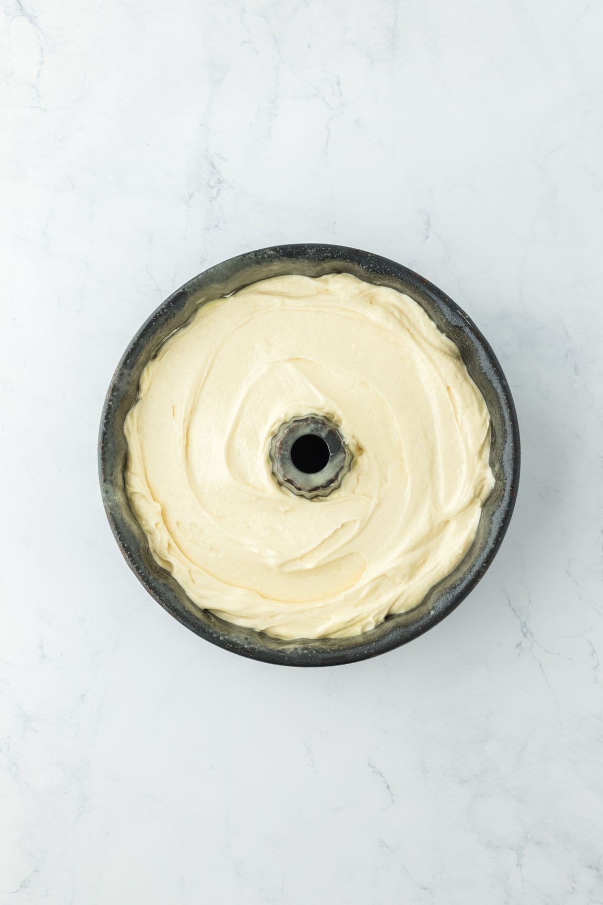 A bundt pan filled with creamy, pale yellow cake batter, ready for baking