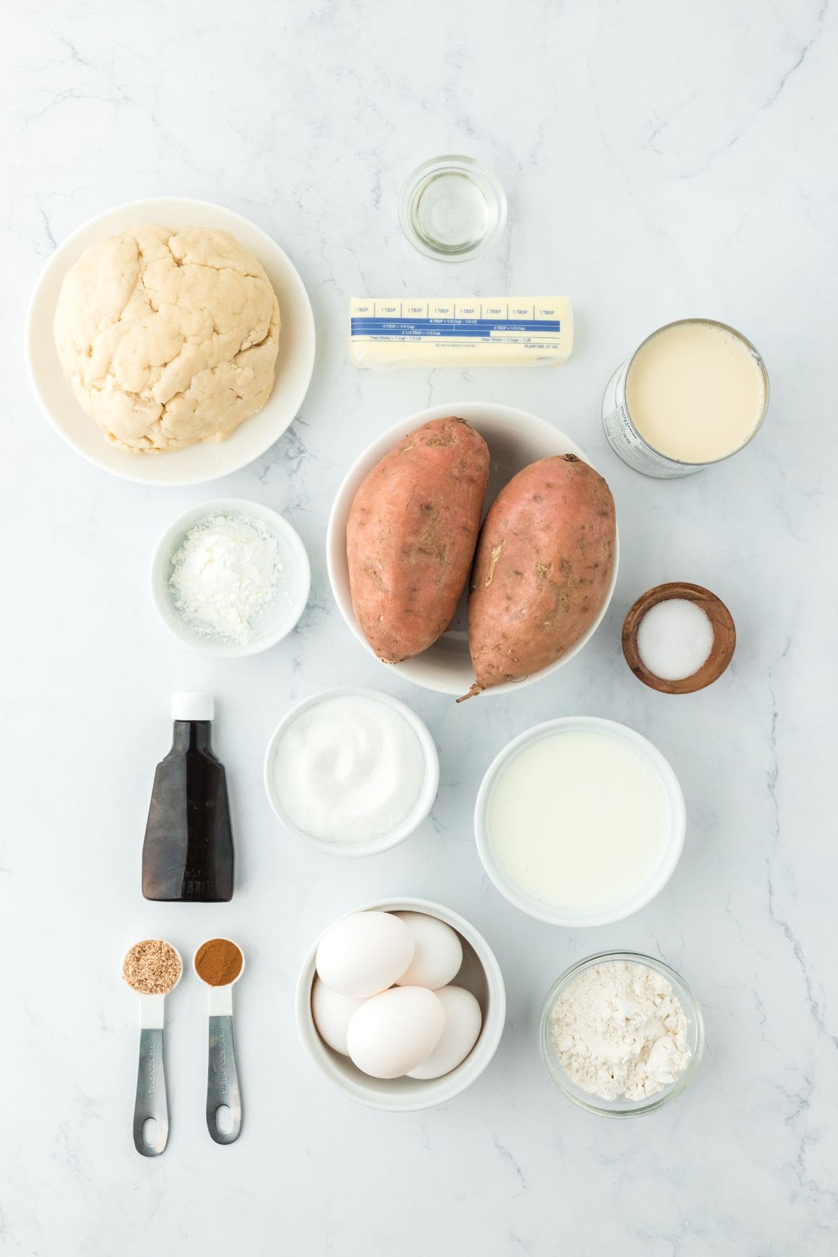 Overhead shot of ingredients for making double crusted sweet potato on a white surface before baking