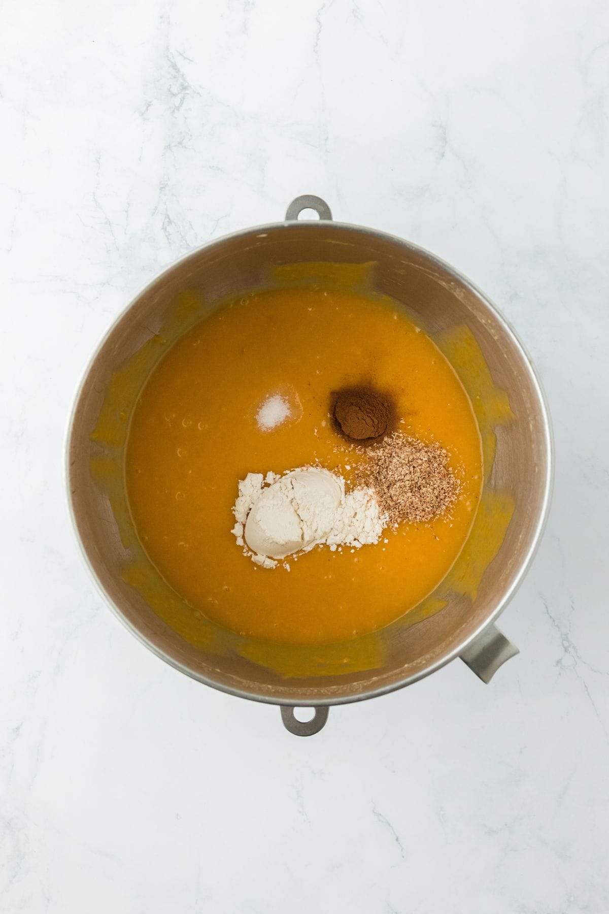 Flour, spices, and salt added to the sweet potato pie mixture in a mixing bowl