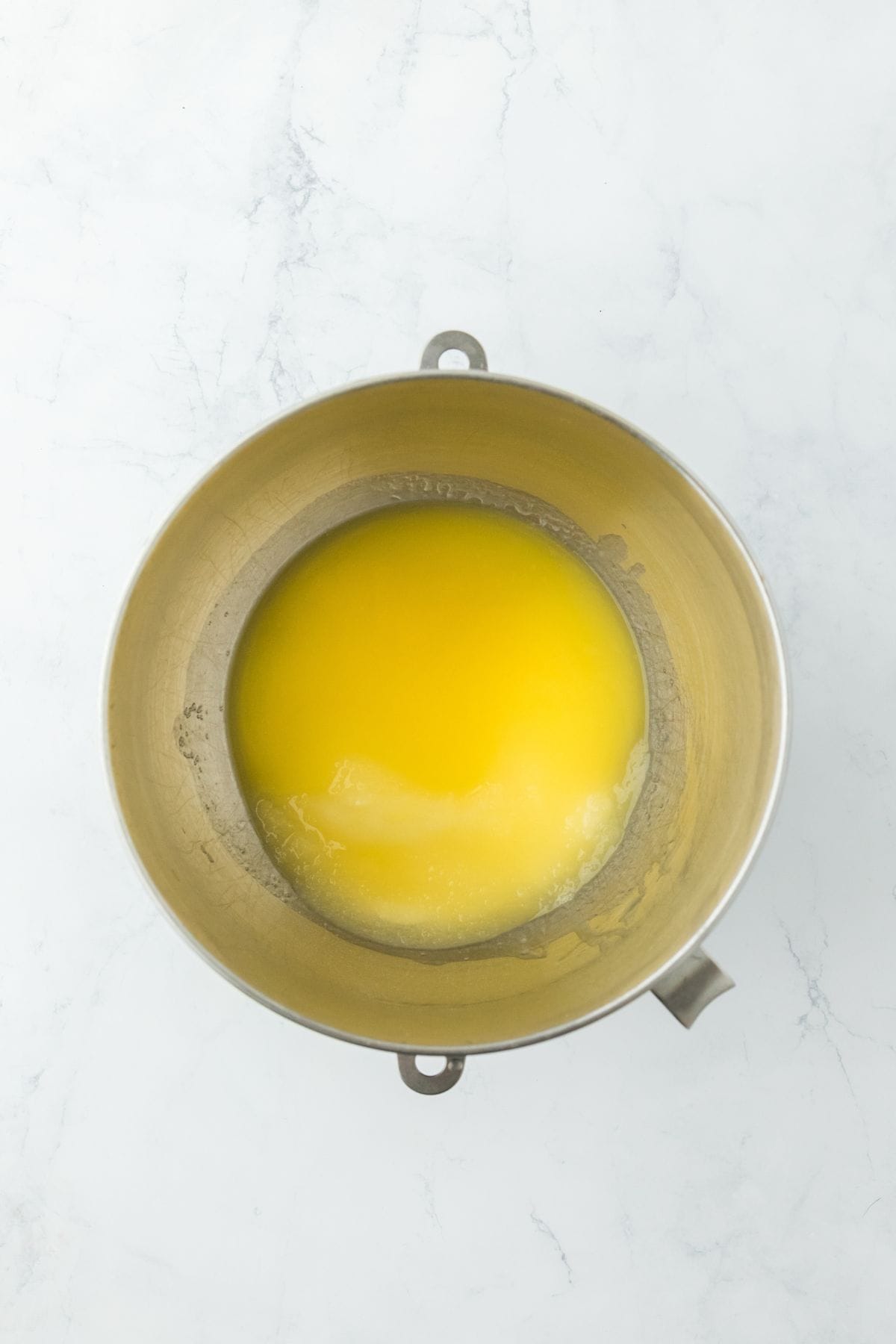 A mixing bowl with melted butter and sugar mixed inside