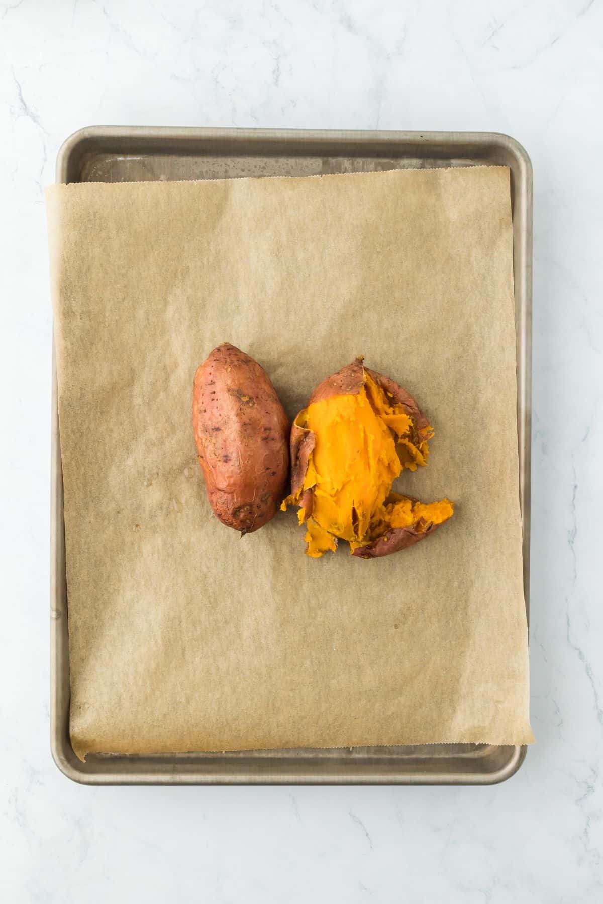 Roasted sweet potatoes split open on the same tray