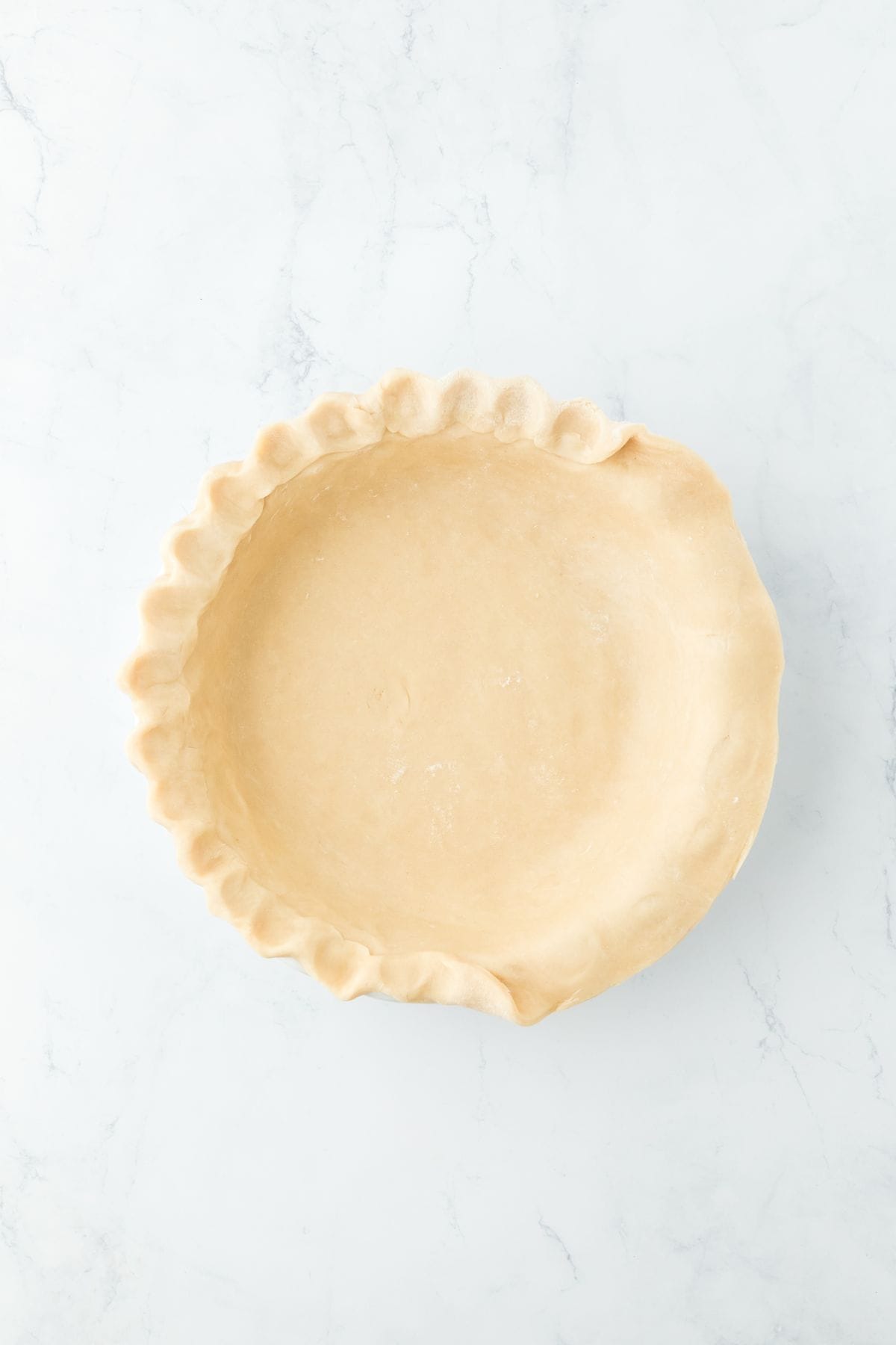 An unbaked pie crust with the edges crimped for decoration