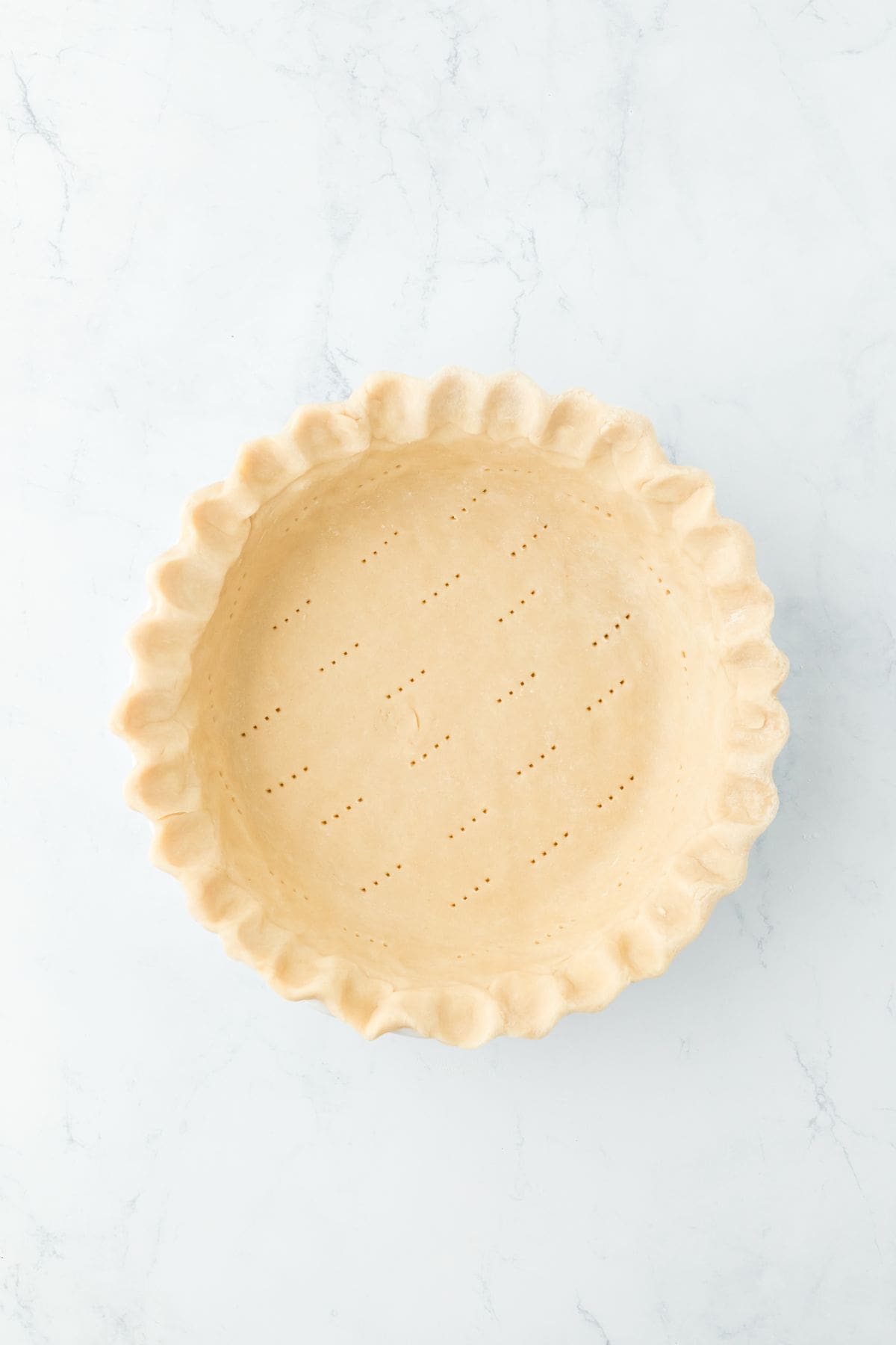 An unbaked pie crust with fork pricks at the bottom to prevent bubbling