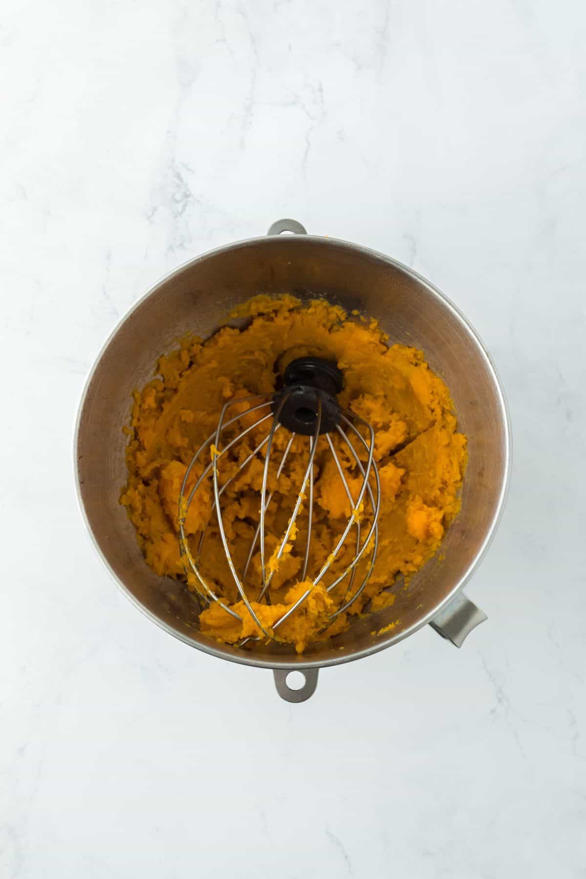 A mixing bowl filled with mashed sweet potatoes, prepped for pie filling